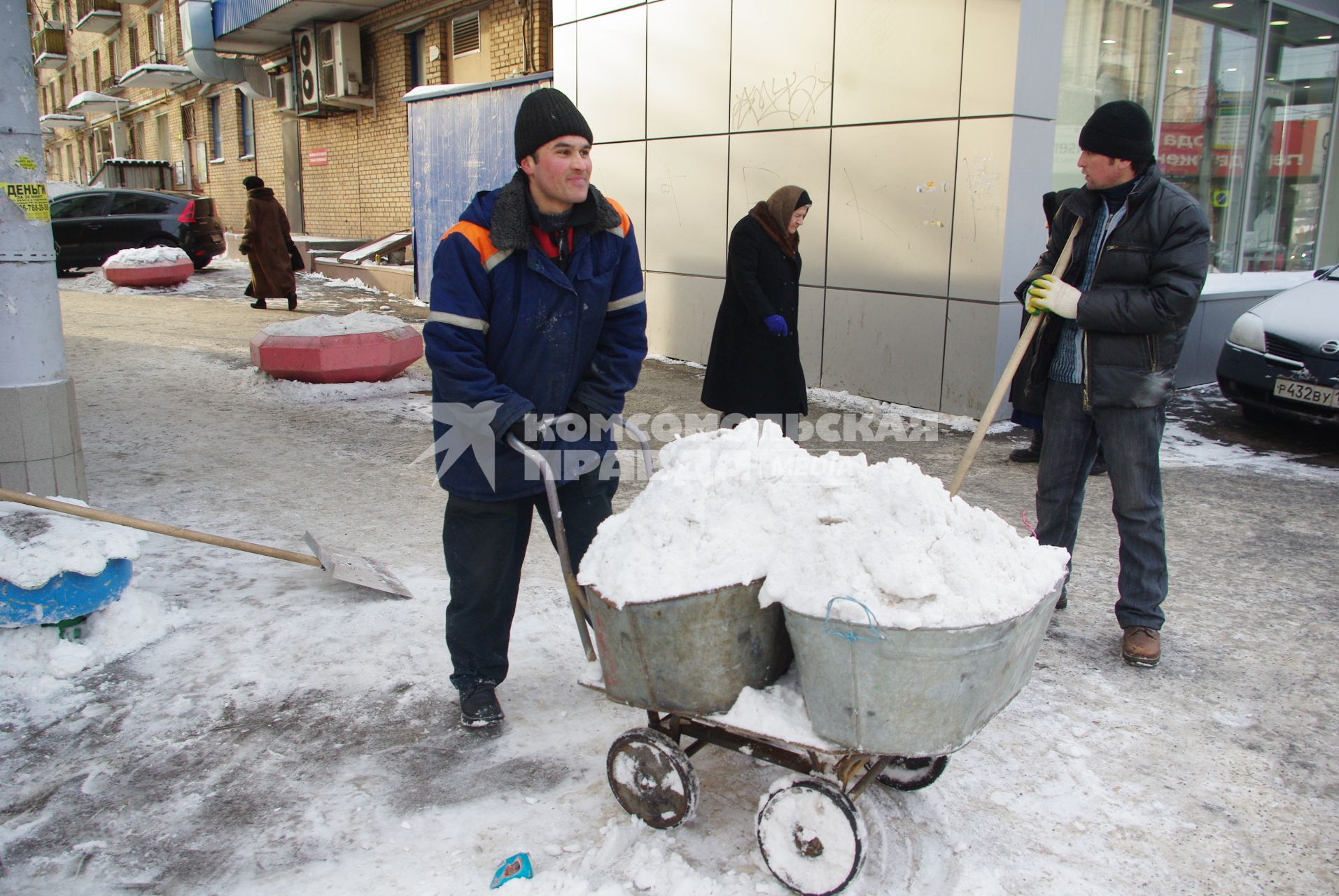 Гастарбайтеры убирают снег в корыто на тележке, Москва, 17 февраля 2011 года.