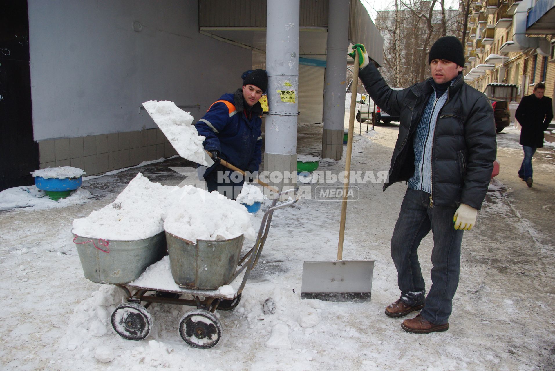 Гастарбайтеры убирают снег в корыто на тележке, Москва, 17 февраля 2011 года.