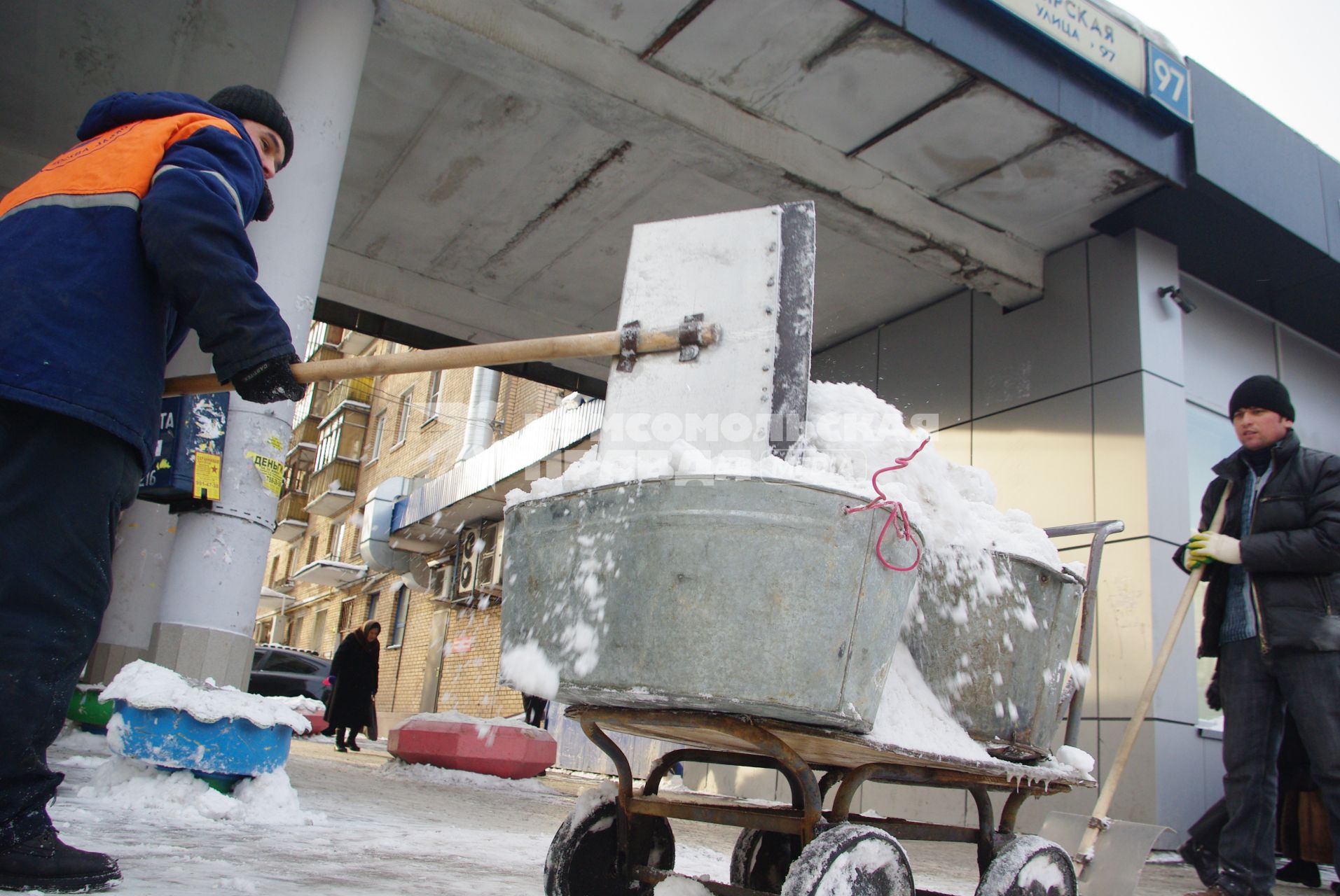 Гастарбайтеры убирают снег в корыто на тележке, Москва, 17 февраля 2011 года.