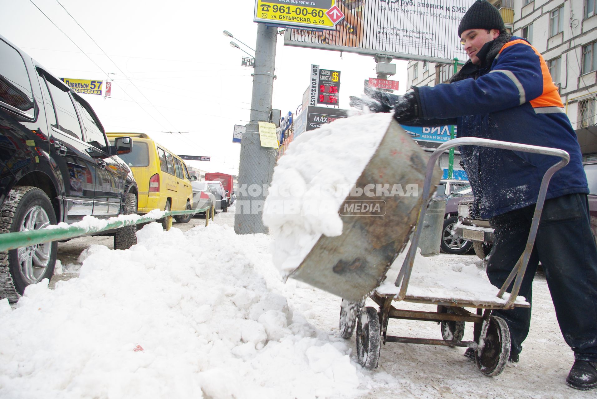 Гастарбайтеры убирают снег в корыто на тележке, Москва, 17 февраля 2011 года.