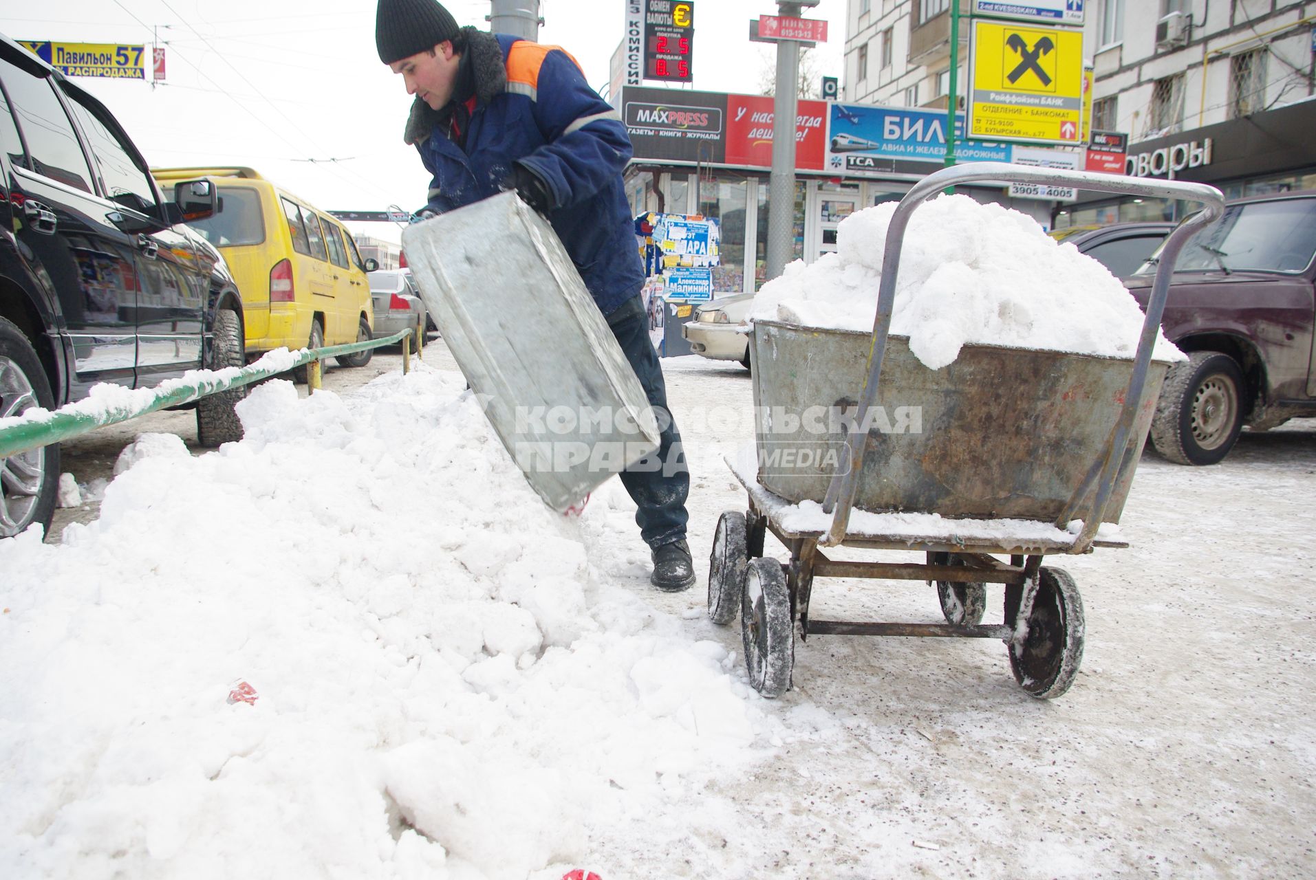 Гастарбайтеры убирают снег в корыто на тележке, Москва, 17 февраля 2011 года.