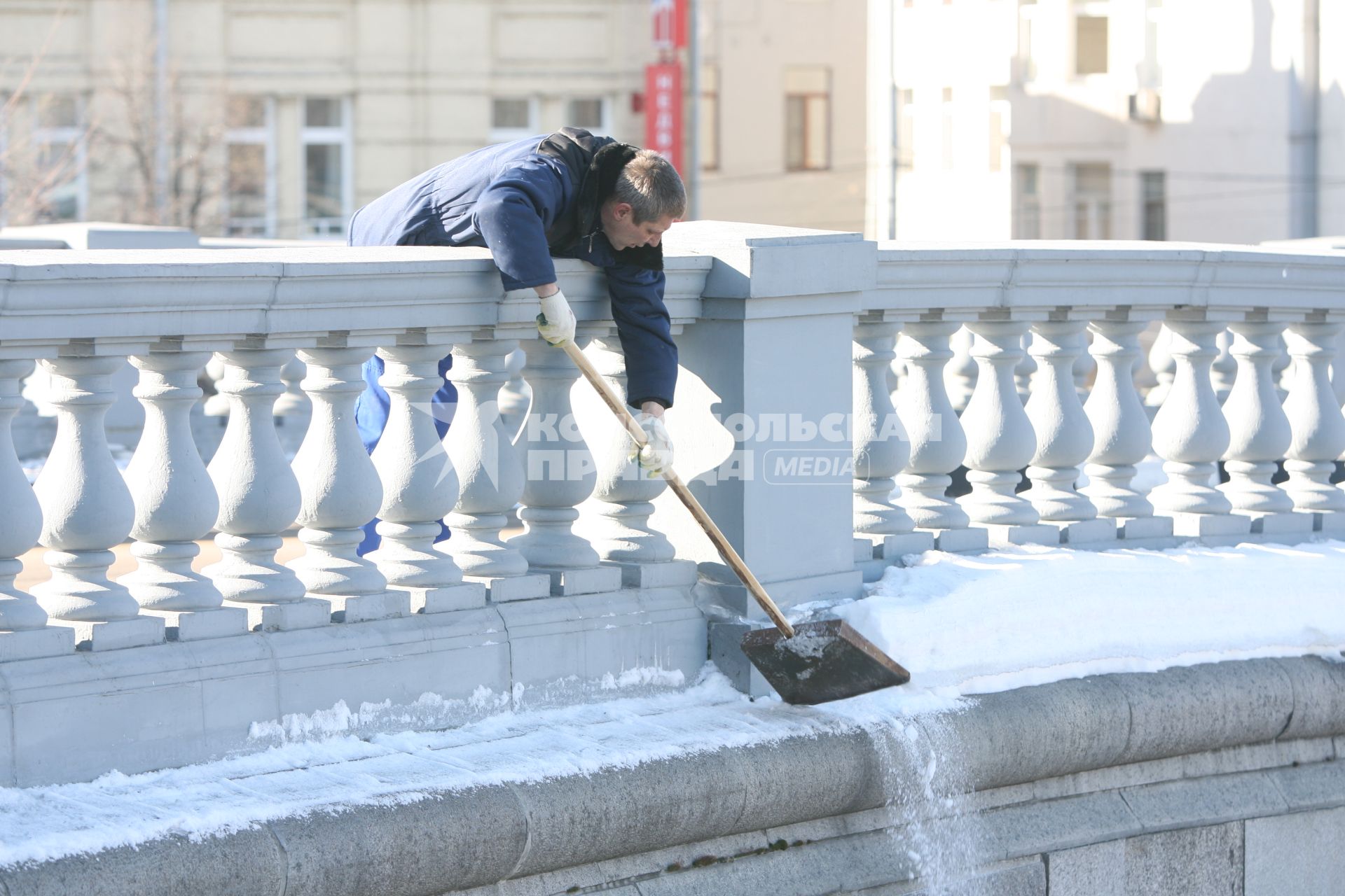 Мужчина лопатой сбрасывает снег из труднодоступного места, Москва, 10 марта 2011 года