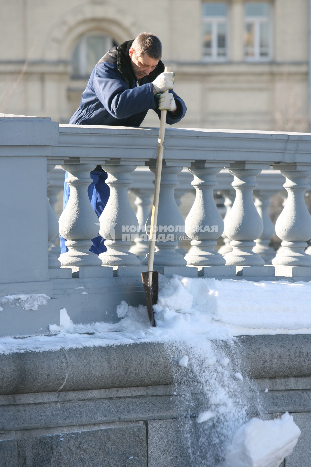 Мужчина лопатой сбрасывает снег из труднодоступного места, Москва, 10 марта 2011 года