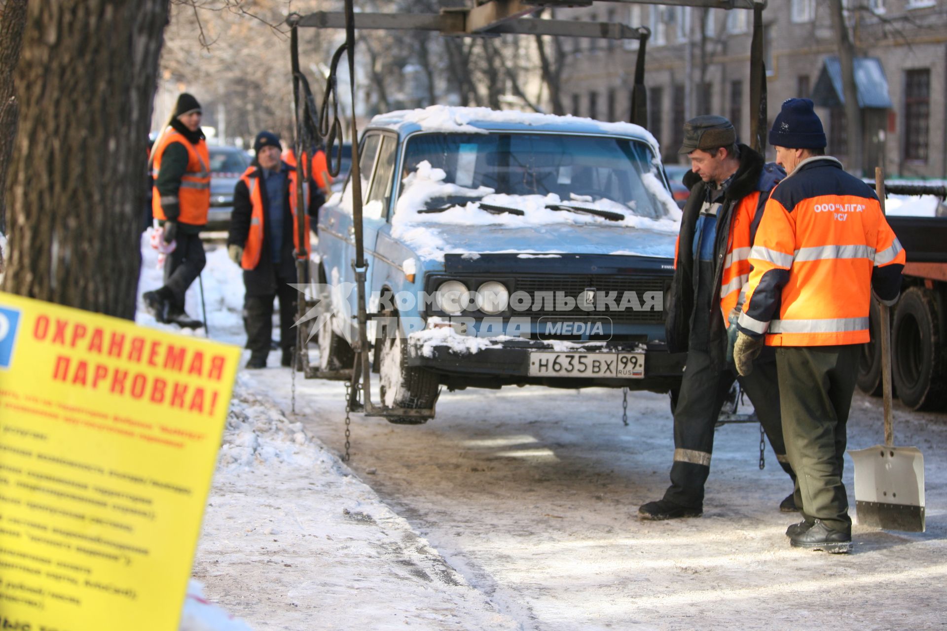 Эвакуатор поднимает автомобили, стоящие вдоль дороги, для очистки под ними снега, Москва, 2 марта 2011 года.