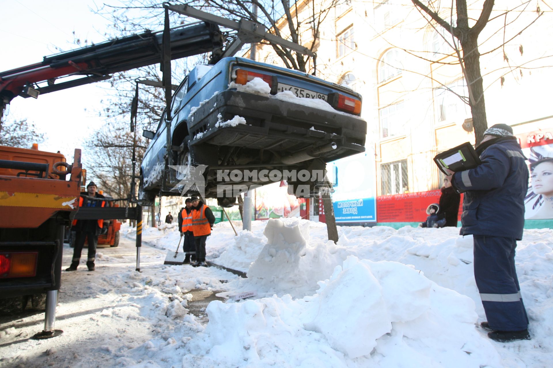 Эвакуатор поднимает автомобили, стоящие вдоль дороги, для очистки под ними снега, Москва, 2 марта 2011 года.