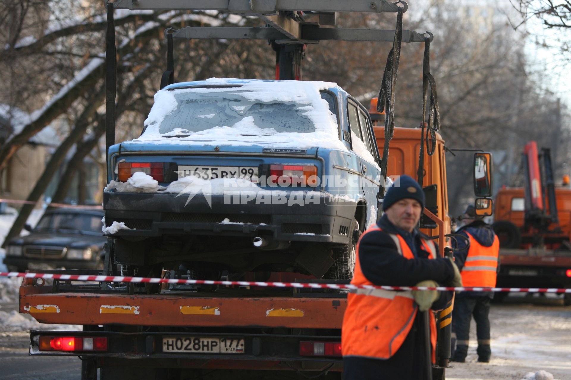 Эвакуатор поднимает автомобили, стоящие вдоль дороги, для очистки под ними снега, Москва, 2 марта 2011 года.