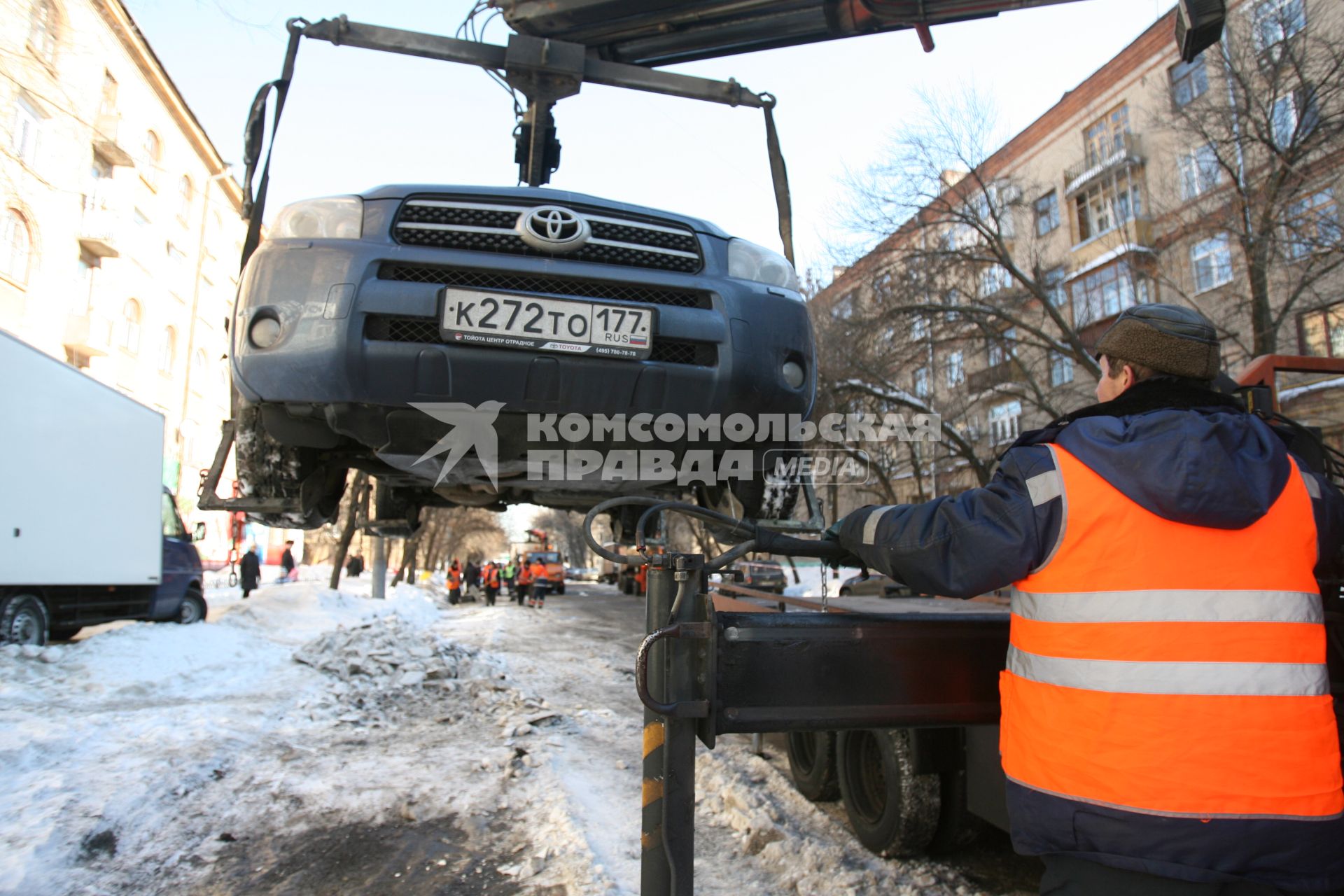 Эвакуатор поднимает автомобили, стоящие вдоль дороги, для очистки под ними снега, Москва, 2 марта 2011 года.