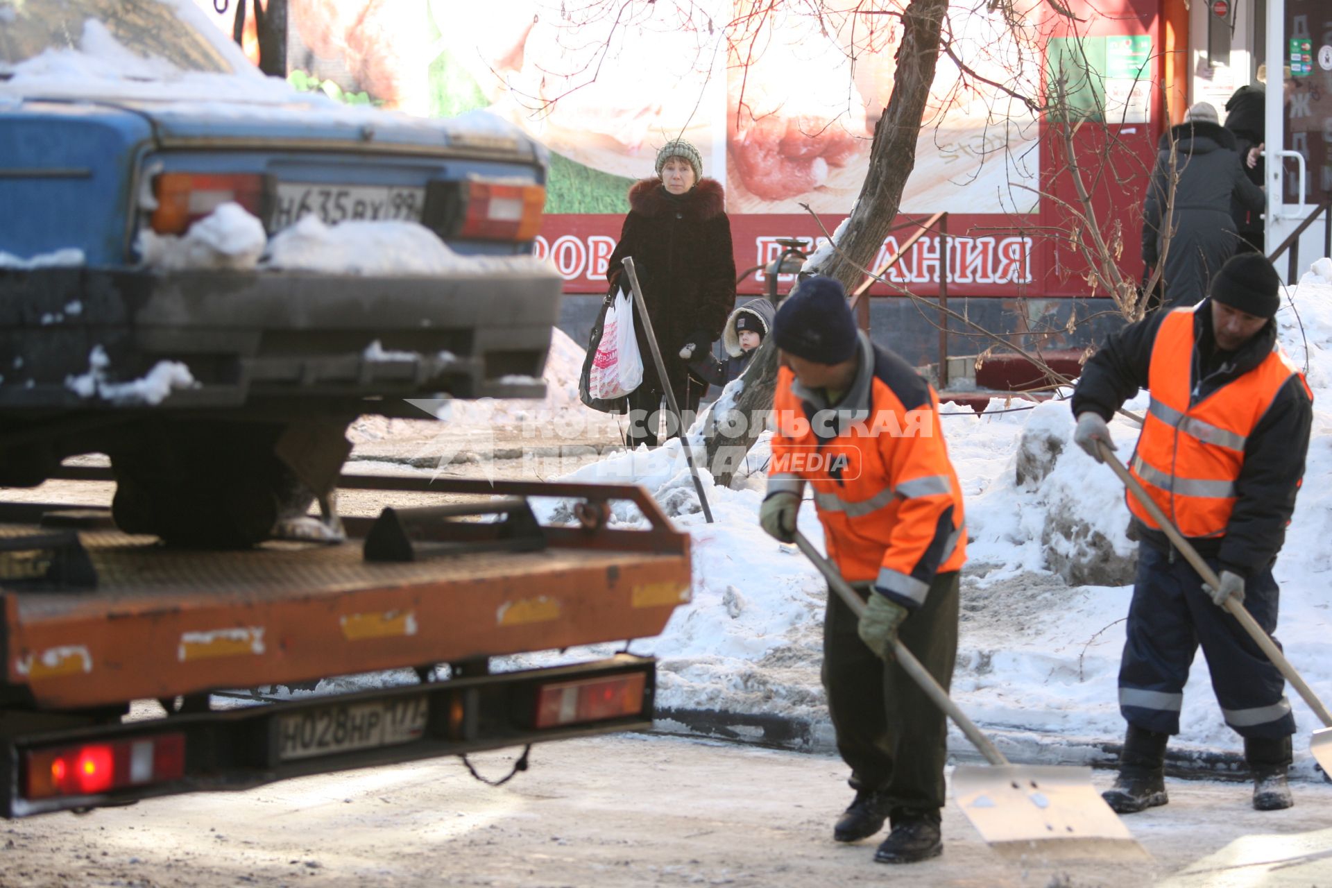 Эвакуатор поднимает автомобили, стоящие вдоль дороги, для очистки под ними снега, Москва, 2 марта 2011 года.