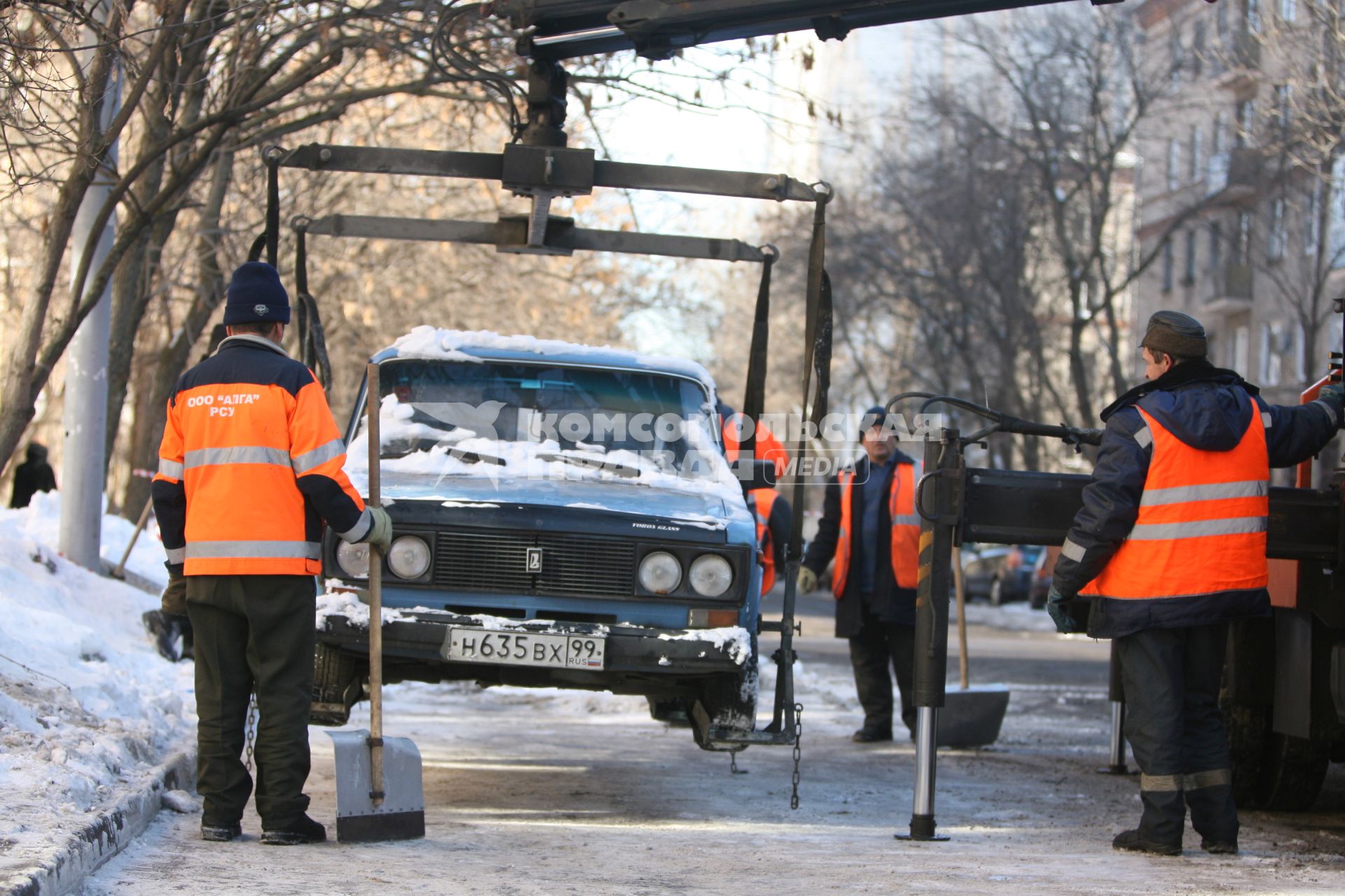 Эвакуатор поднимает автомобили, стоящие вдоль дороги, для очистки под ними снега, Москва, 2 марта 2011 года.