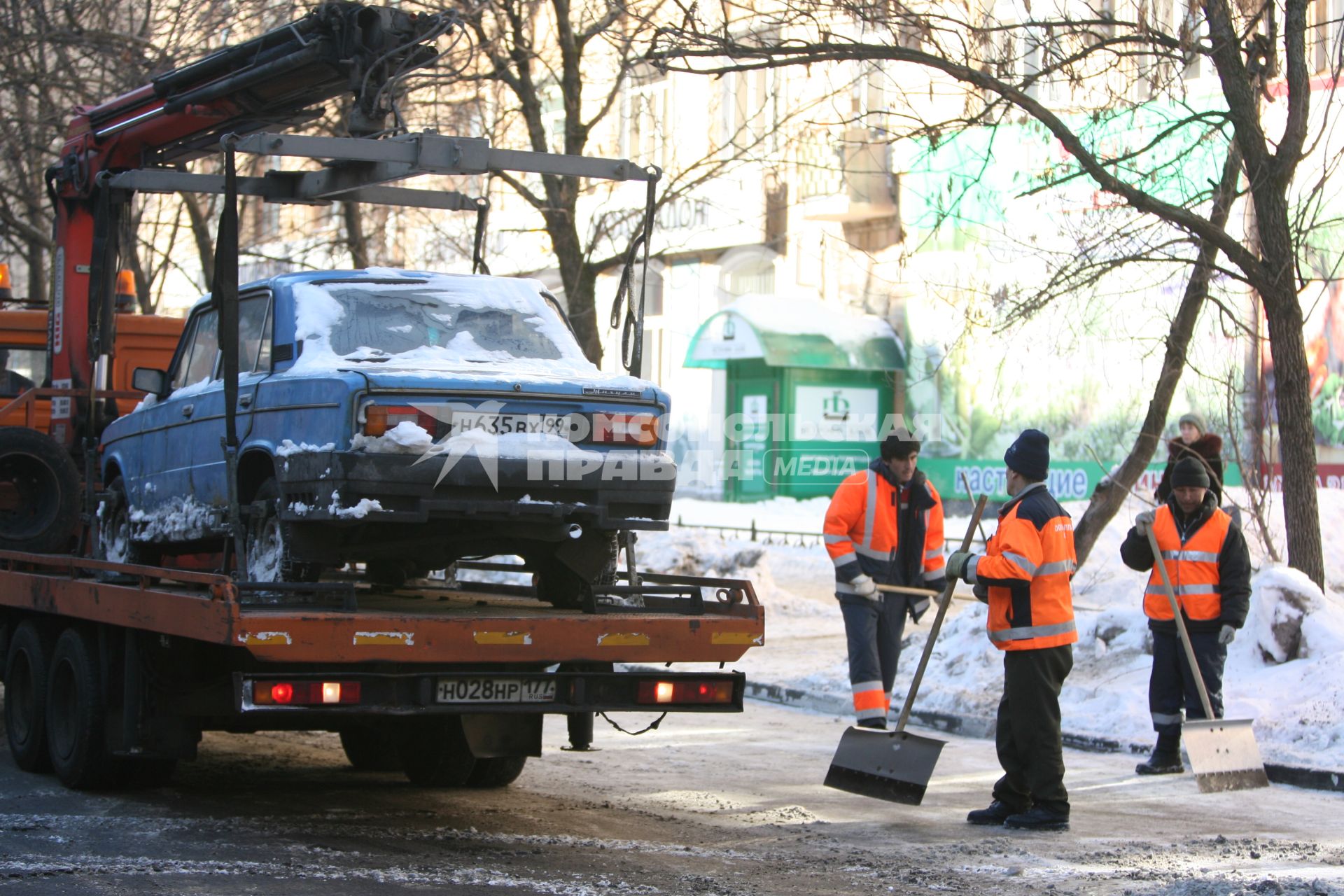 Эвакуатор поднимает автомобили, стоящие вдоль дороги, для очистки под ними снега, Москва, 2 марта 2011 года.