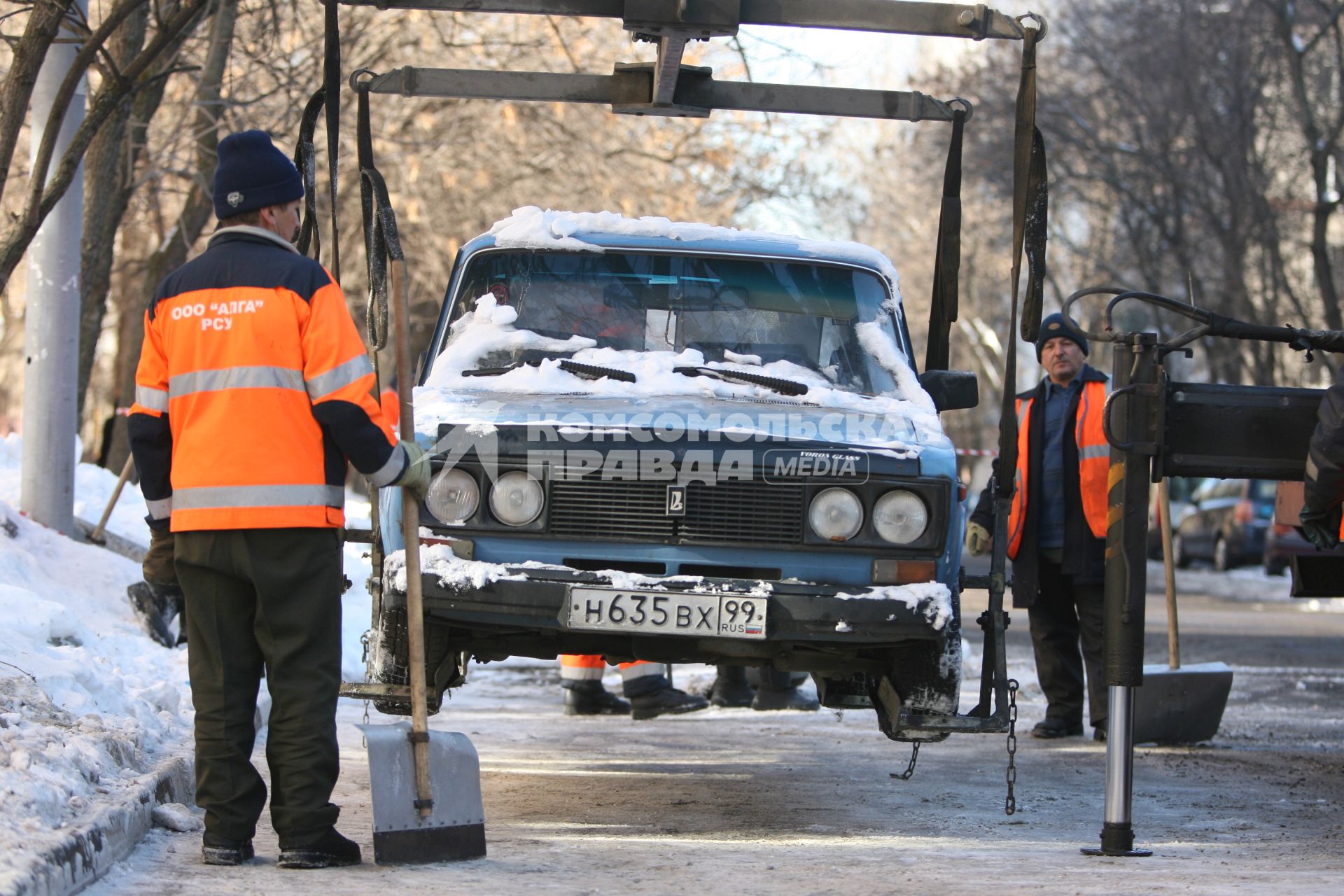 Эвакуатор поднимает автомобили, стоящие вдоль дороги, для очистки под ними снега, Москва, 2 марта 2011 года.