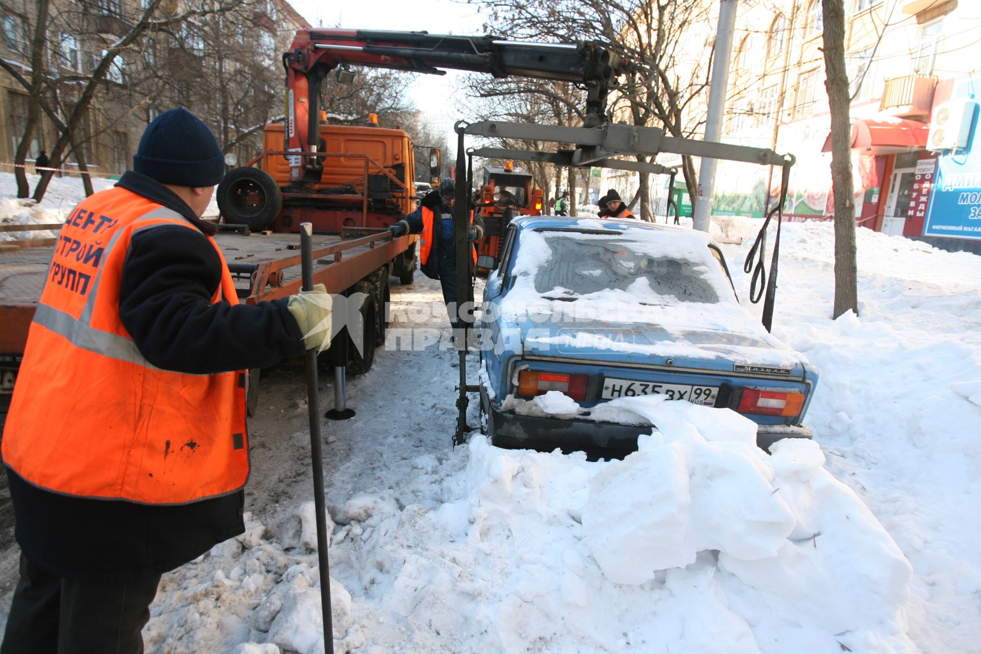 Эвакуатор поднимает автомобили, стоящие вдоль дороги, для очистки под ними снега, Москва, 2 марта 2011 года.