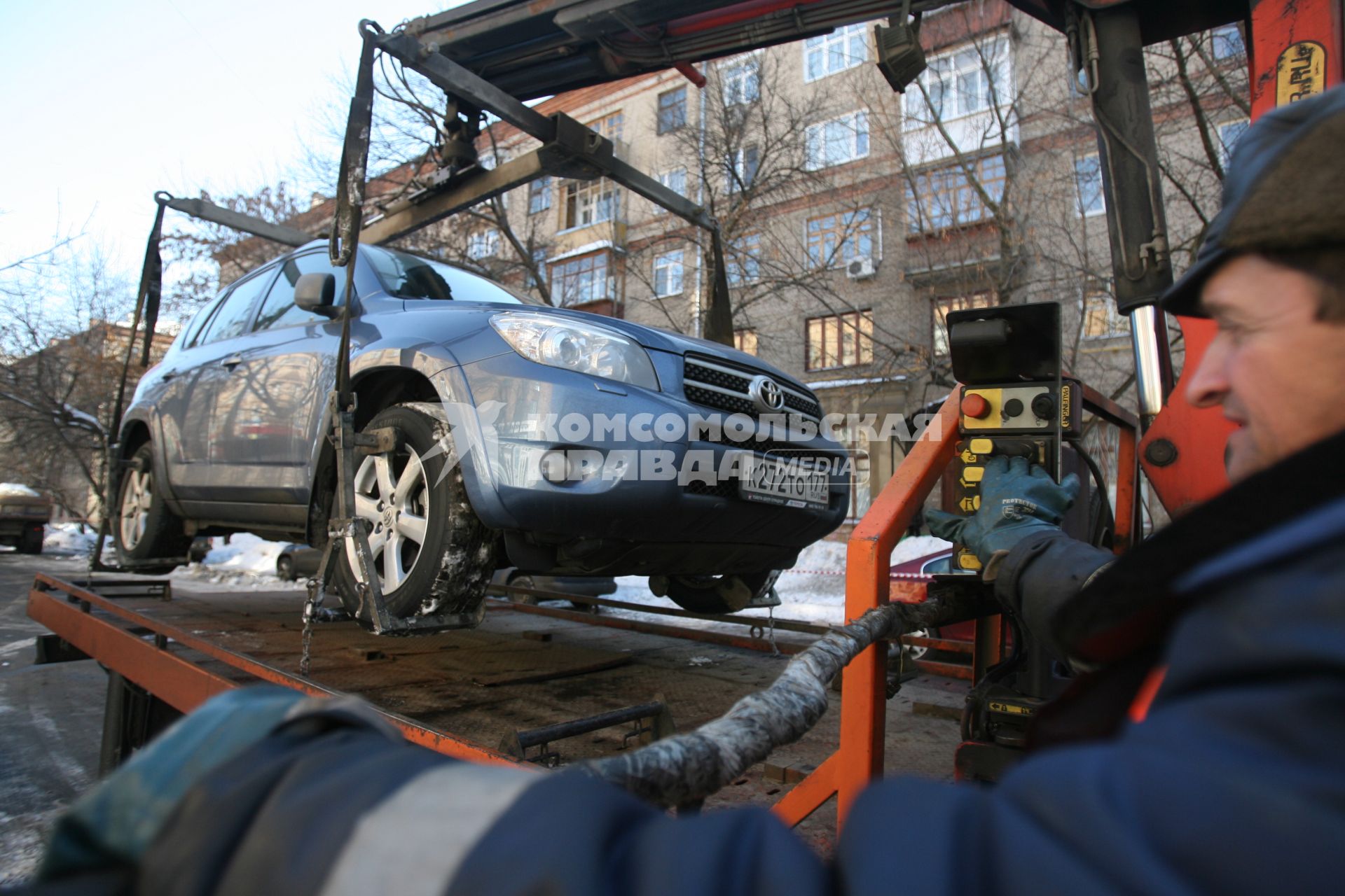 Эвакуатор поднимает автомобили, стоящие вдоль дороги, для очистки под ними снега, Москва, 2 марта 2011 года.