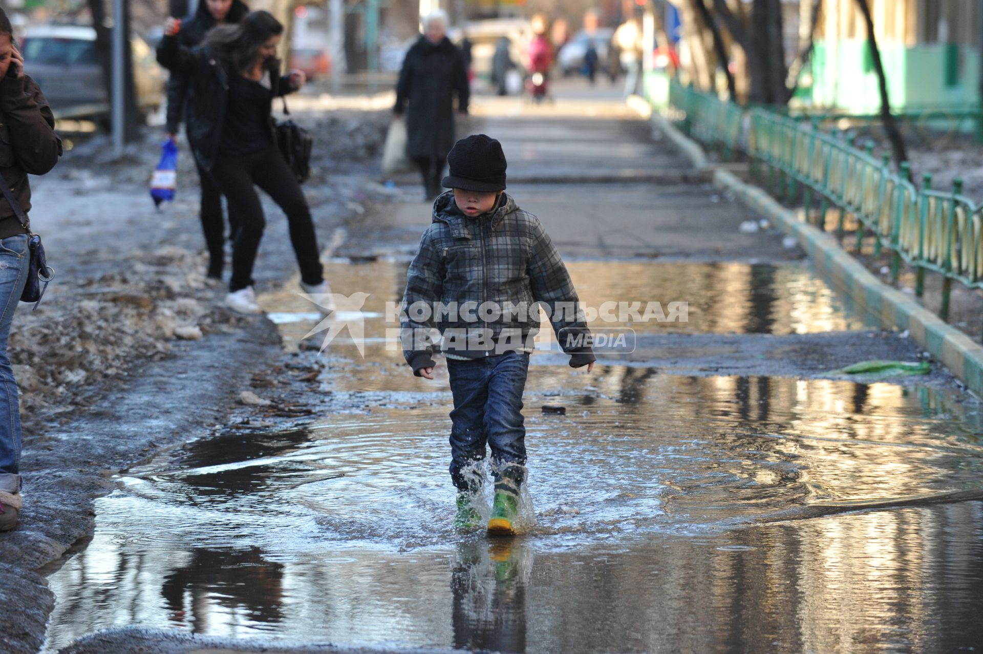 04 апреля 2011 г. Россия, Москва. Мальчик в резиновых сапогах идет по луже.