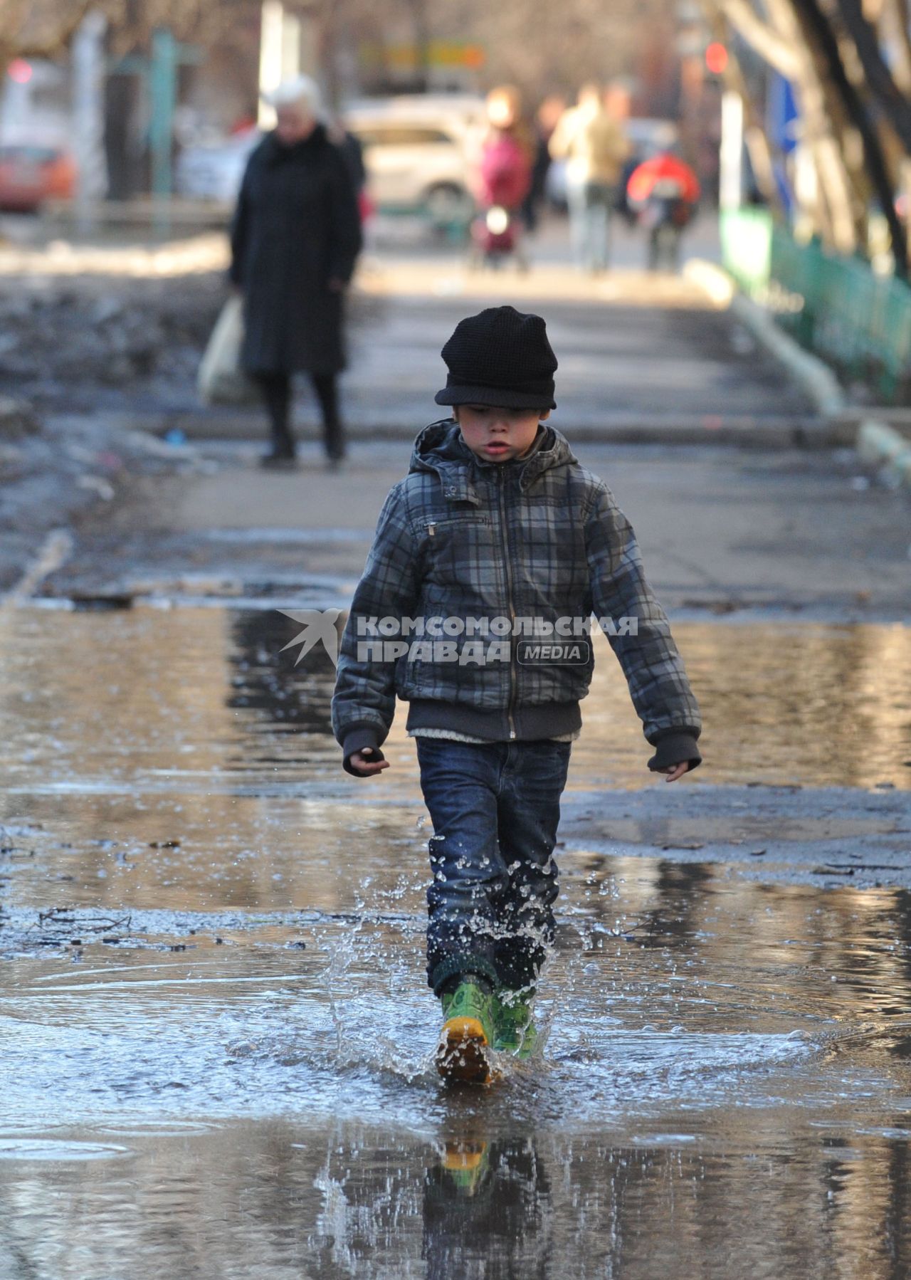04 апреля 2011 г. Россия, Москва. Мальчик в резиновых сапогах идет по луже.