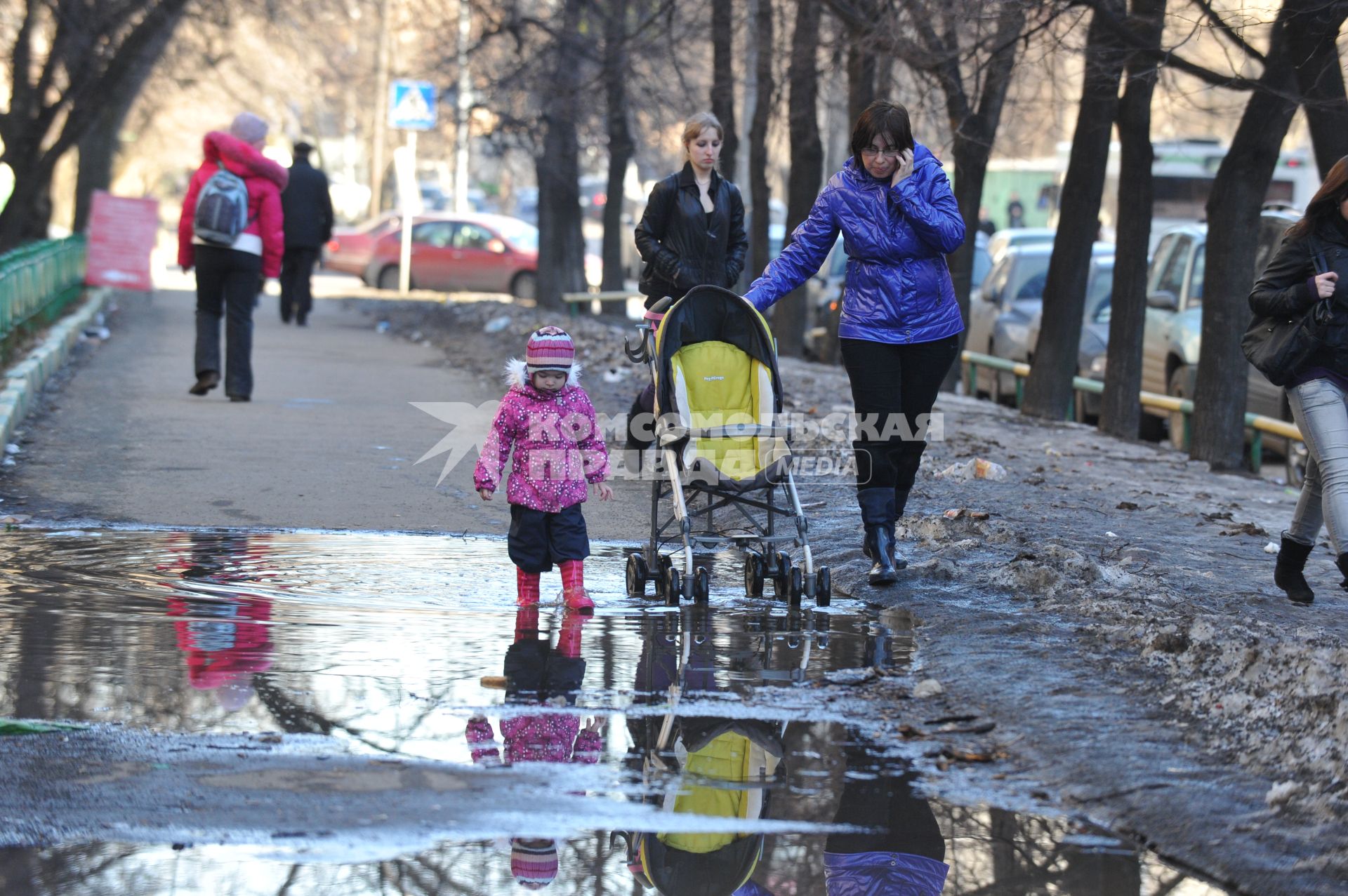 04 апреля 2011 г. Россия, Москва. Дети и их родители. Лужа на тротуаре.