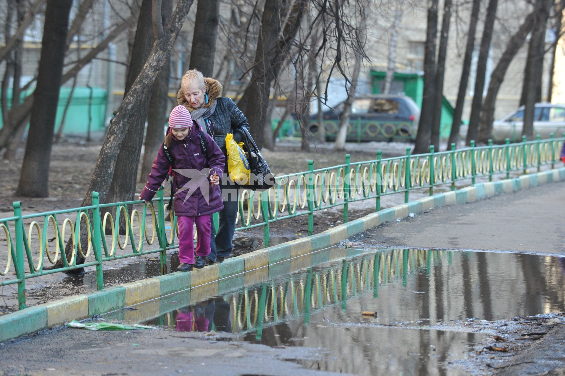 04 апреля 2011 г. Россия, Москва. Дети и их родители. Лужа на тротуаре.