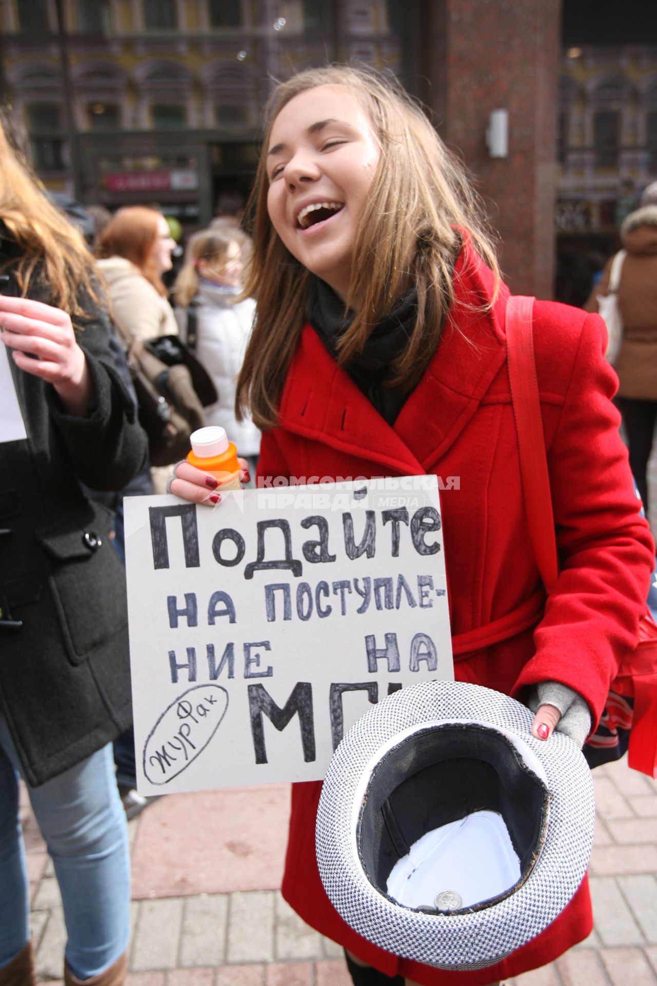 Девушка с плакатом \"Подайте на поступление в МГУ\" со шляпой в руках стоит на Арбате, Москва, 10 апреля 2011 года