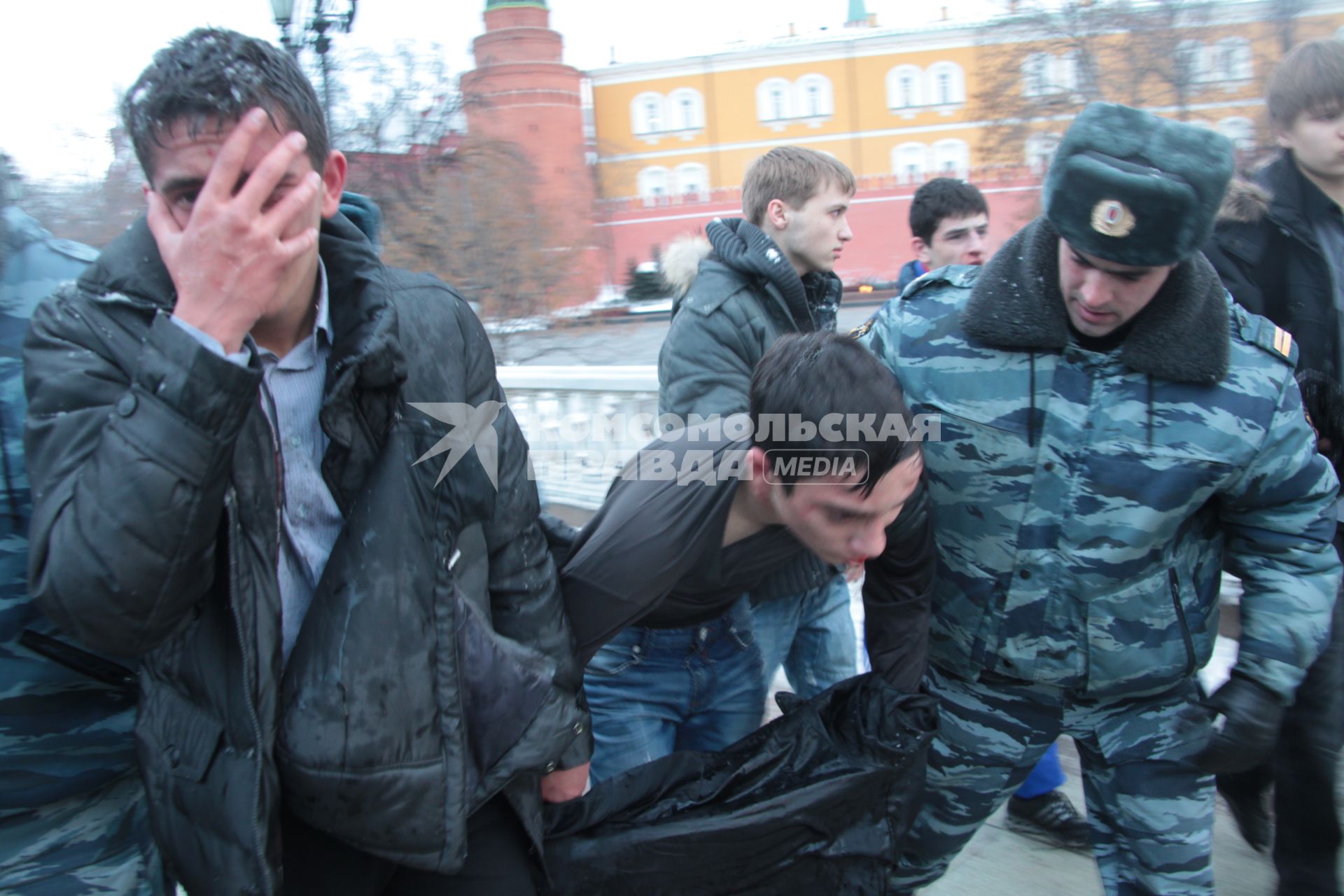 Митинг на Манежной площади, который начался в память о погибшем болельщике СПАРТАКА Егоре Свиридове и перерос в массовые беспорядки и погром. На снимке: Двое избитых похожих на кавказцев людей сопровождаются сотрудником ОМОНа. 11 декабря 2010 года.