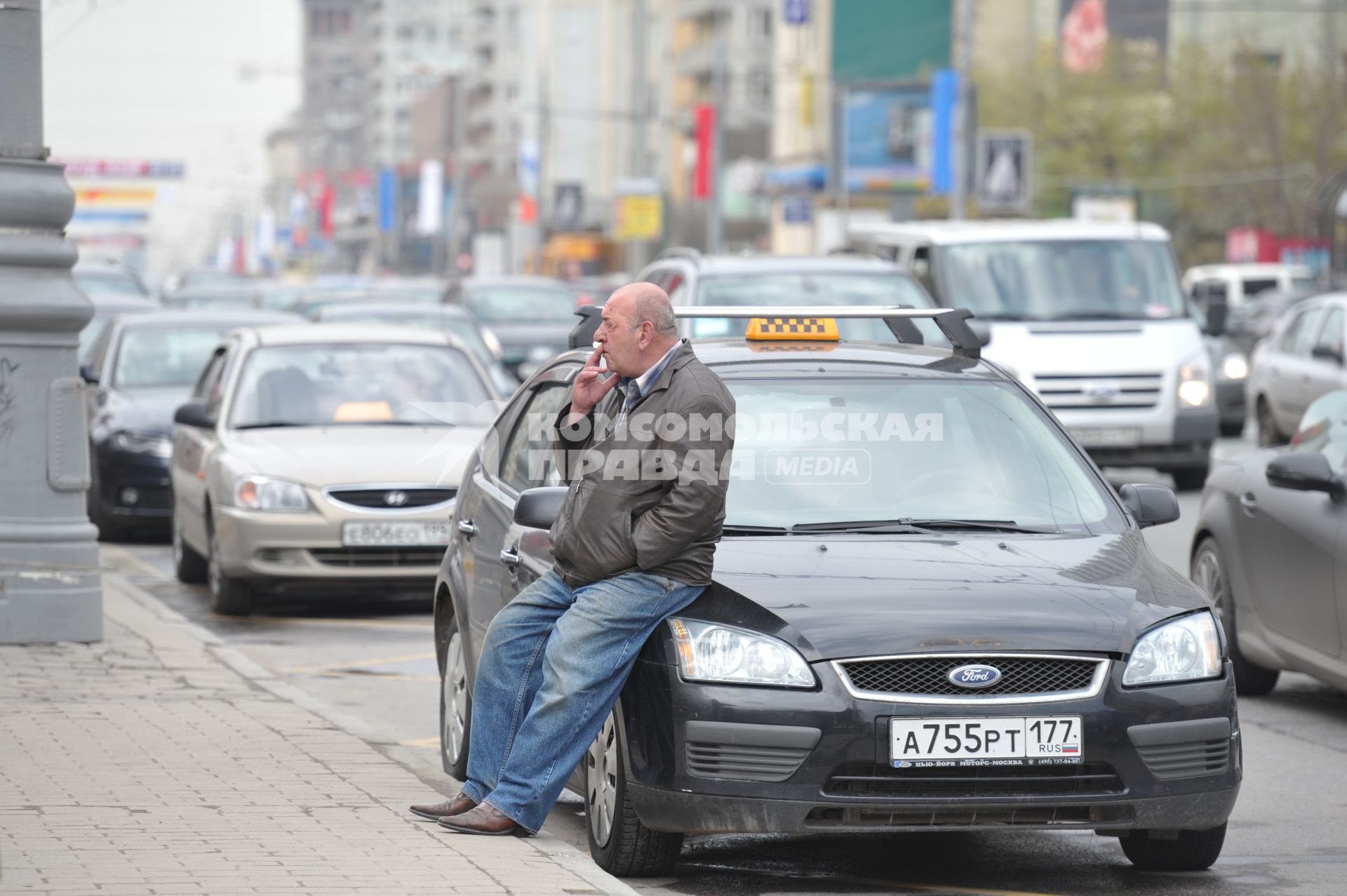 Таксист сидит на машине и курит в ожидании пассажиров, Москва, 5 мая 2011 года