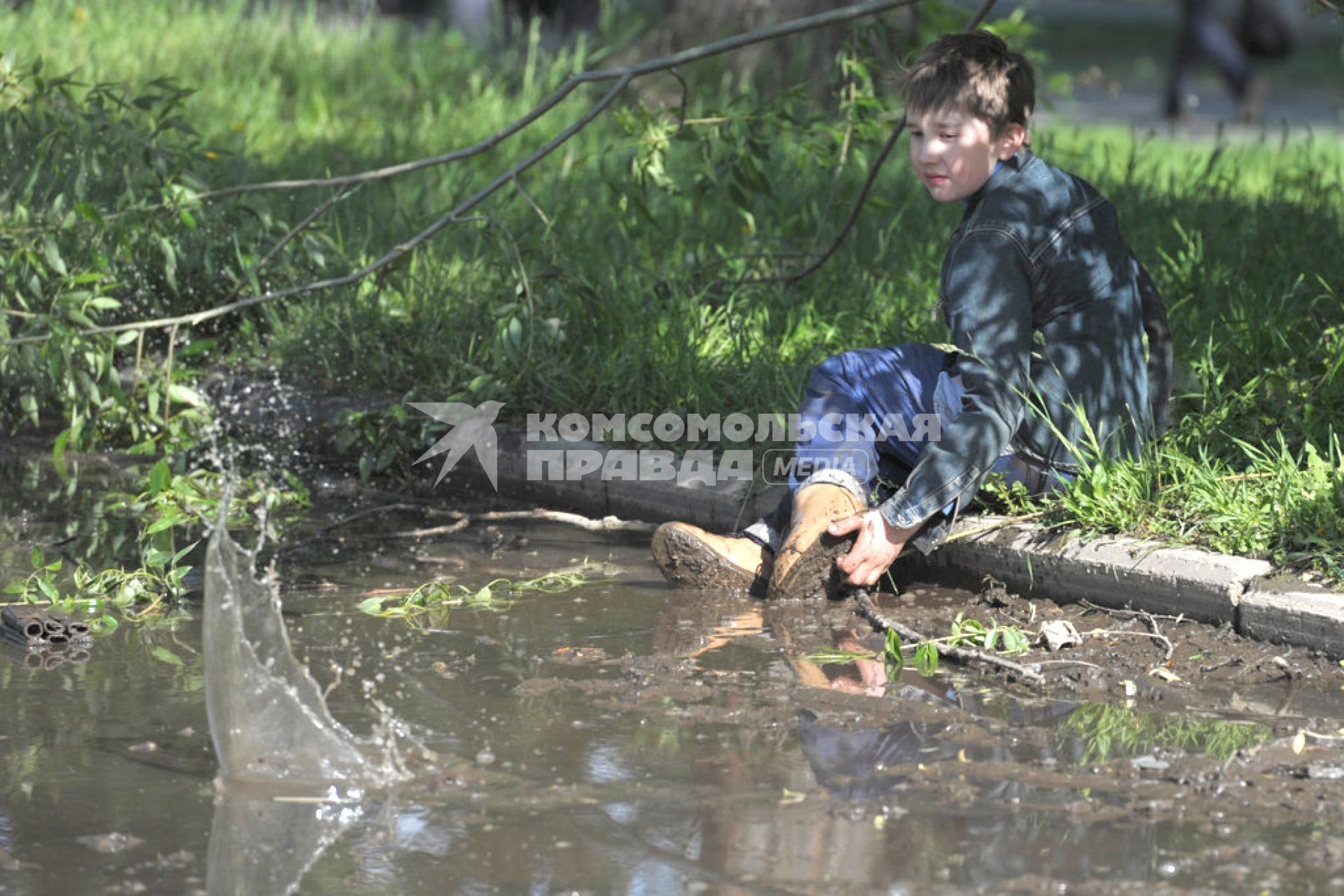 Мальчик сидит на бордюре, свесив ноги в лужу, Иваново, 27 июня 2011 года