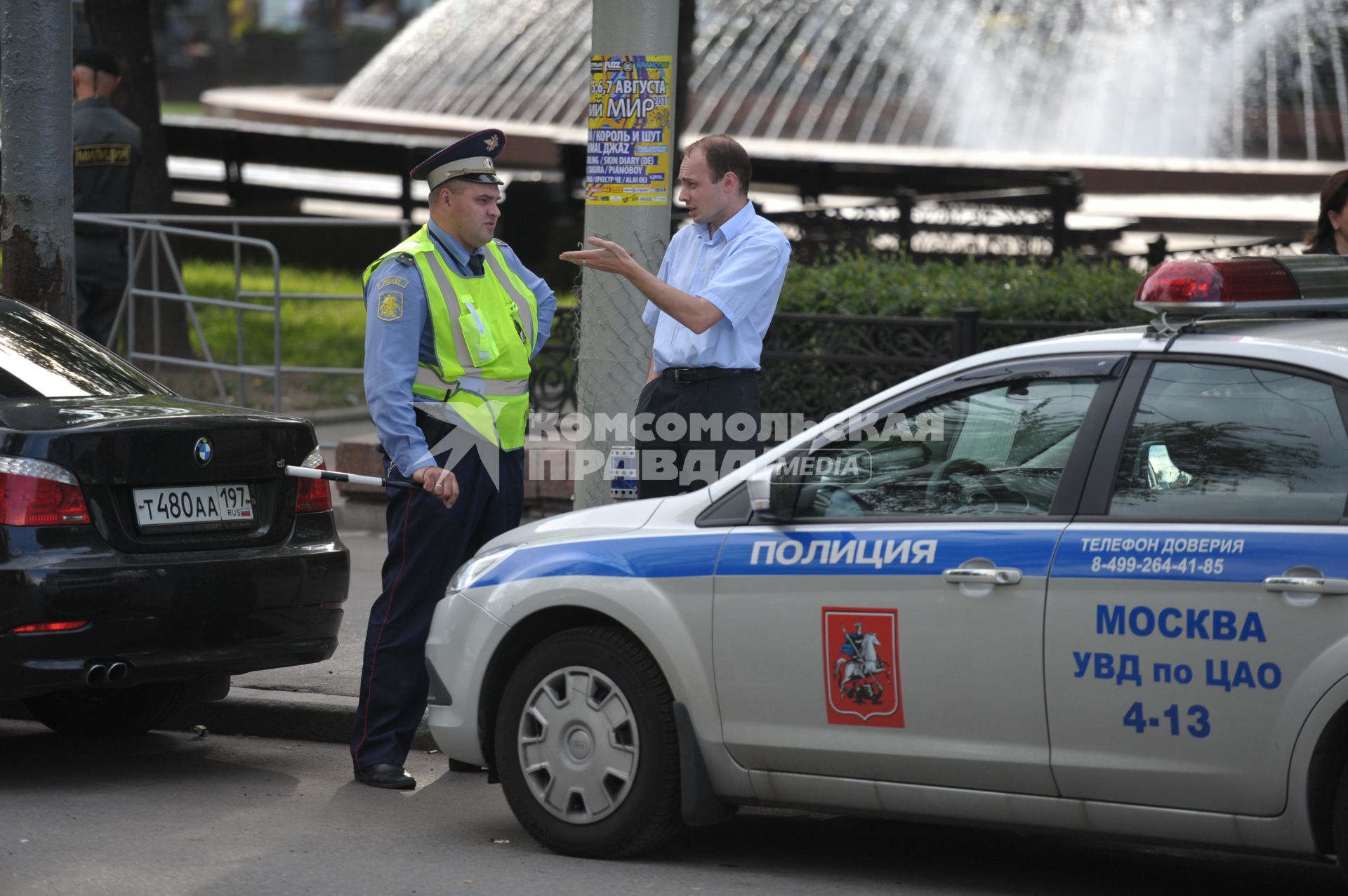 Полицейский у машины с надписью полиция разговаривает с мужчиной в костюме, Москва, 22 июня 2011 года