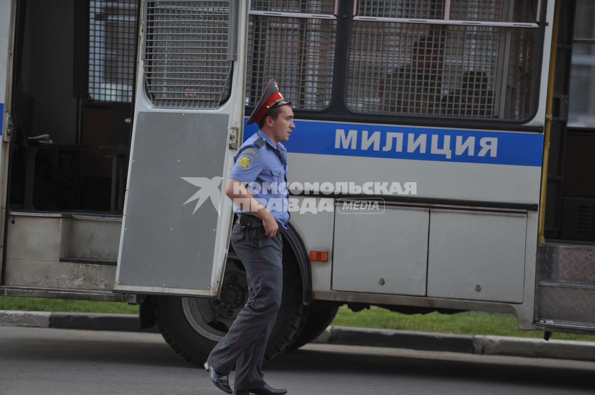 Полицейский идет мимо машины с надписью милиция, Москва, 28 июня 2011 года