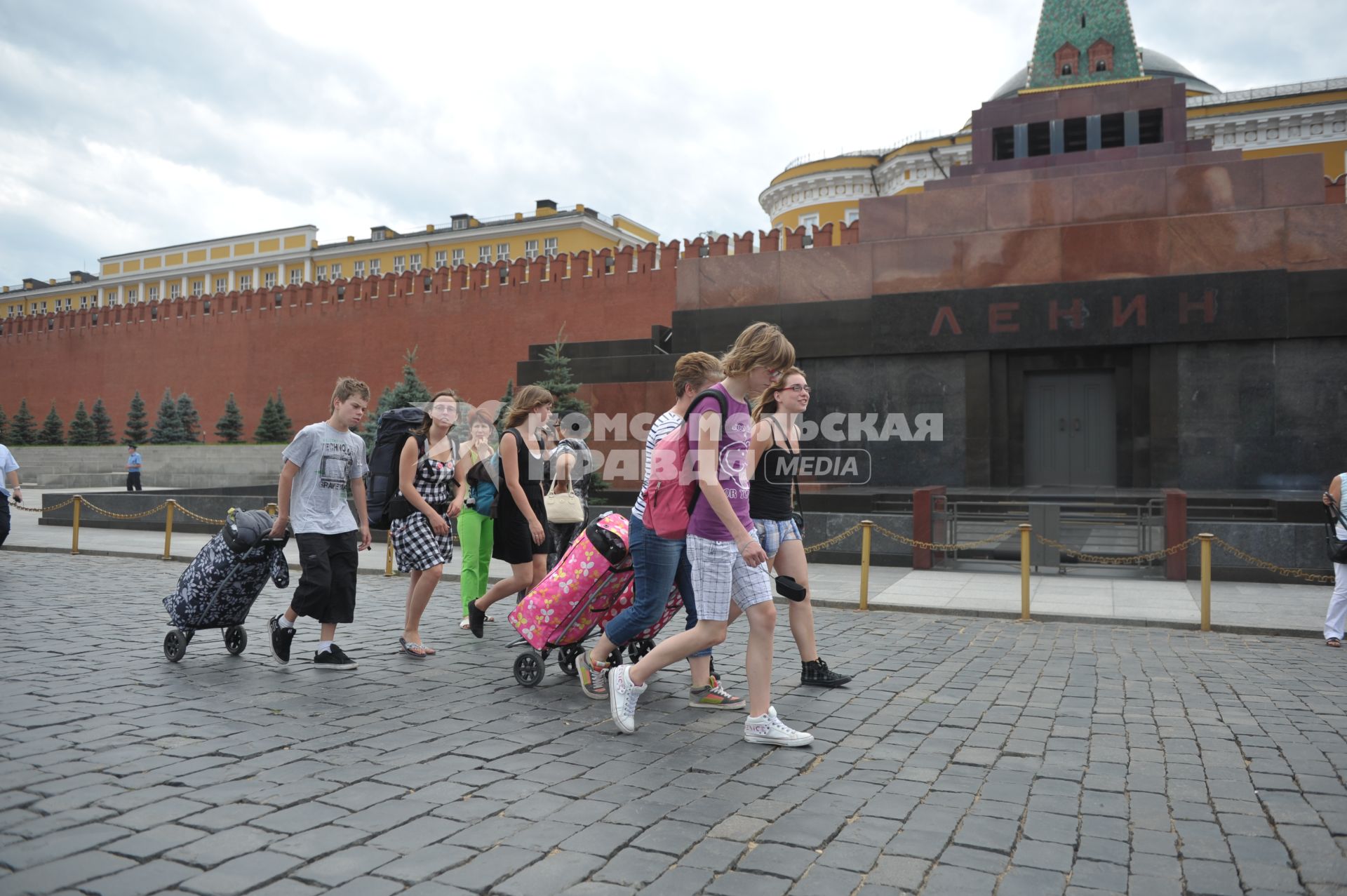 Туристы с чемоданами идут по Красной площади, Москва, 14 июля 2011 года.