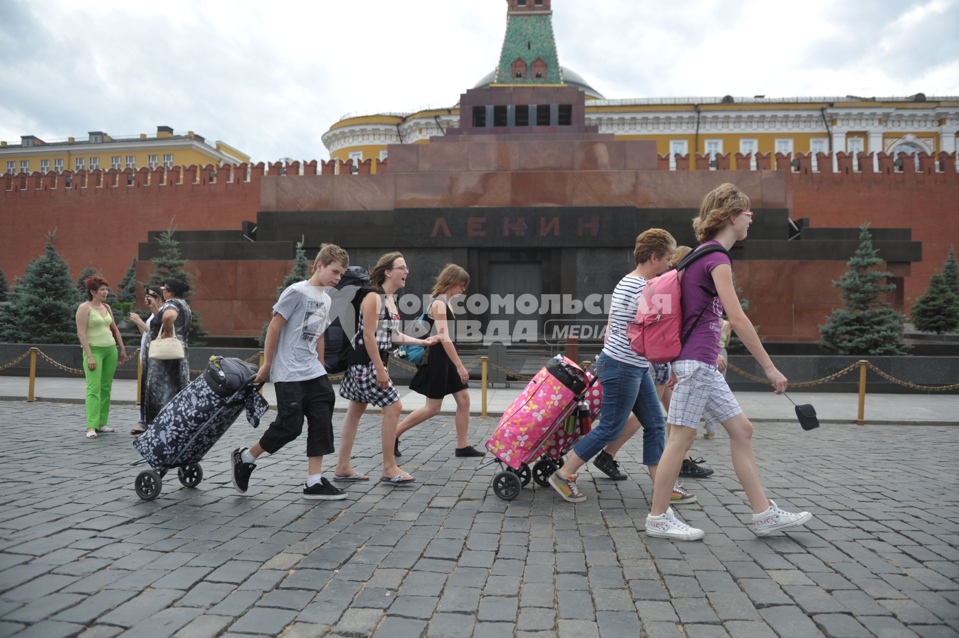 Туристы с чемоданами идут по Красной площади, Москва, 14 июля 2011 года.