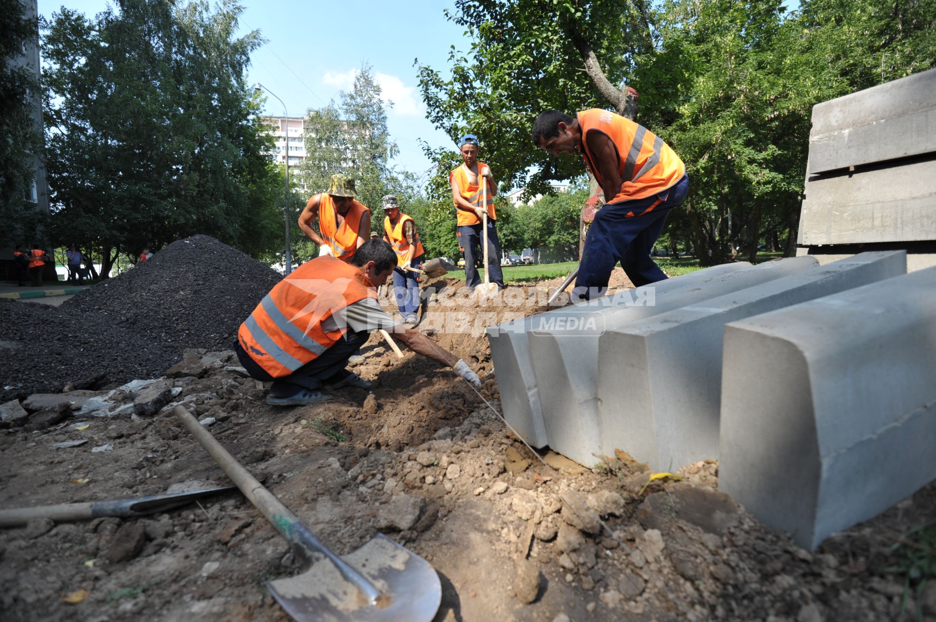 Гастарбайтеры ведут работы у многоэтажного дома- копают лопатами траншеи, Москва, 16 июля 2011 года.