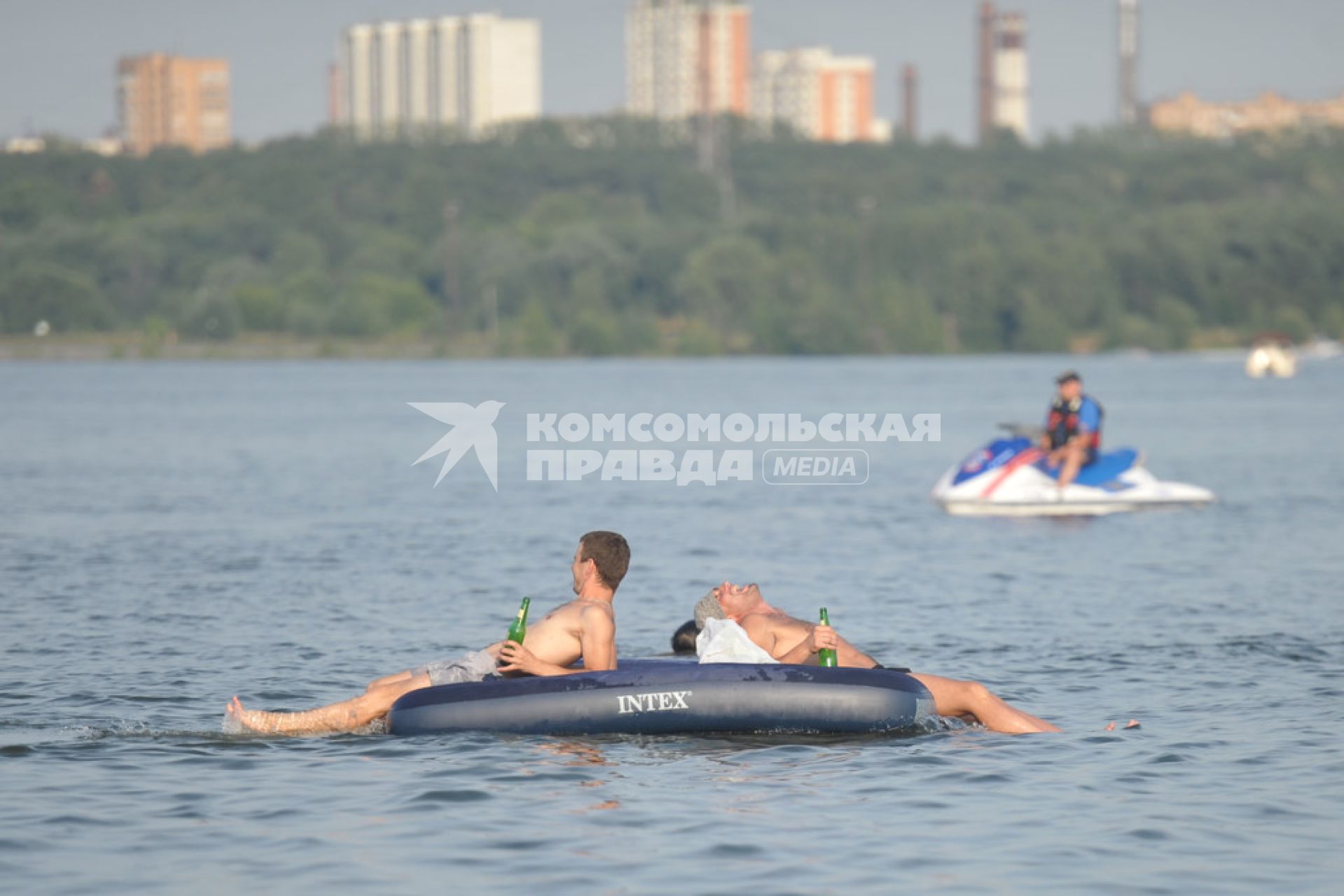 Молодые люди с пивом в руках на надувном матрасе плавают по Москве- реке, Москва, 24 июля 2011 года.