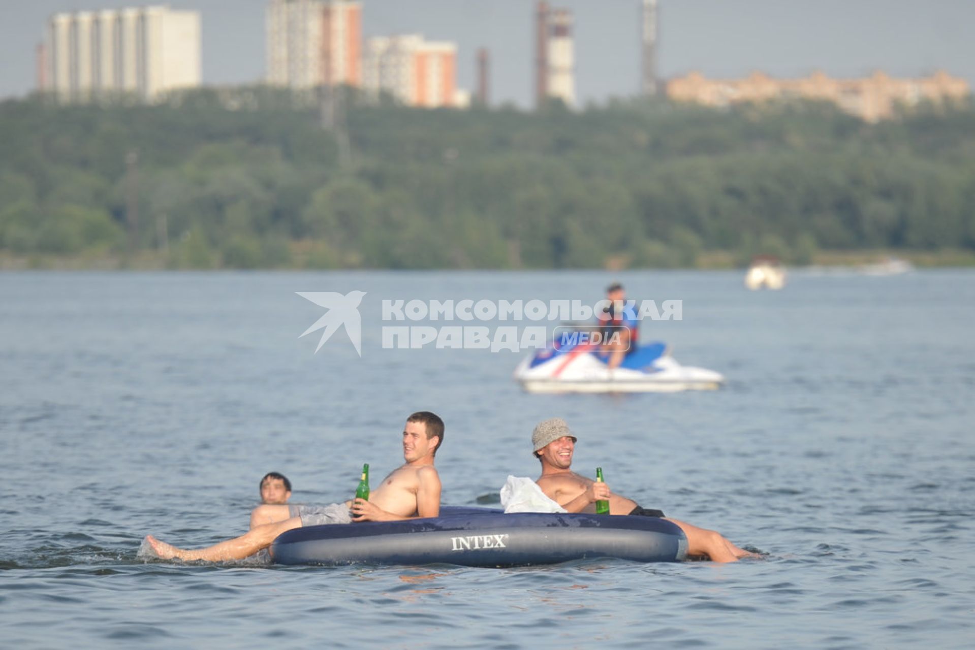 Молодые люди с пивом в руках на надувном матрасе плавают по Москве- реке, Москва, 24 июля 2011 года.