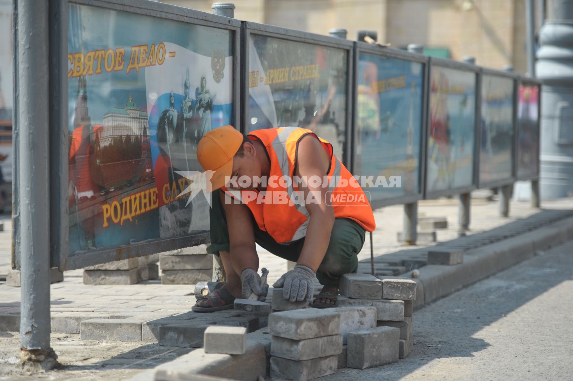 Гастарбайтеры укладывают плитку на тротуар, Москва, 28 июля 2011 года.