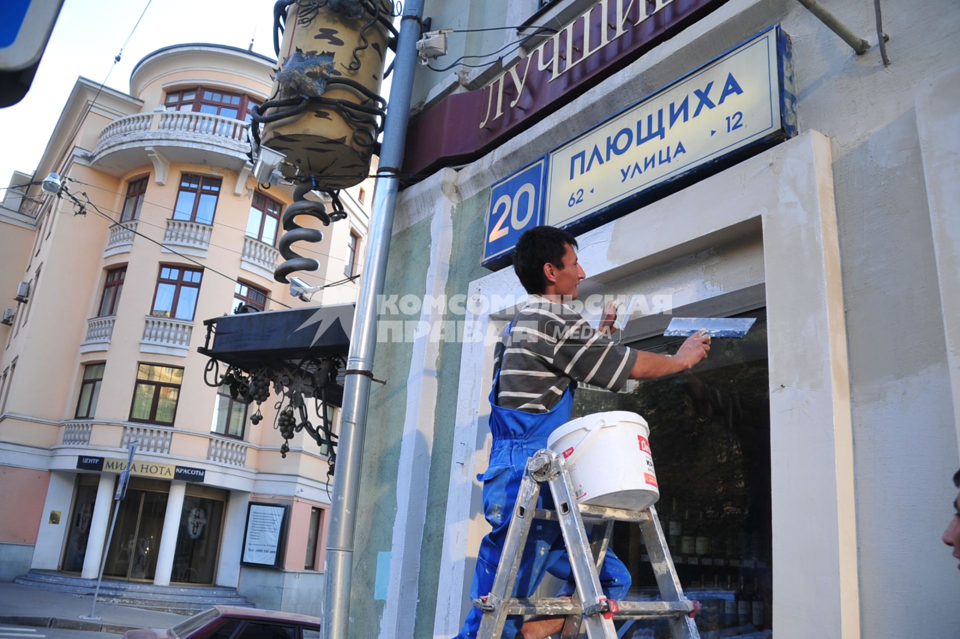 Улица Плющиха. Молодой гастарбайтер ремонтирует фасад здания по адресу Плющиха 20. 16 августа 2011 года.