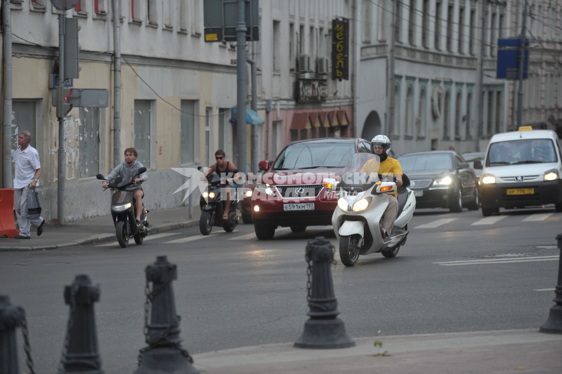 Скутеры и мопеды на дороге города среди машин, Москва, 26 июля 2011 года.