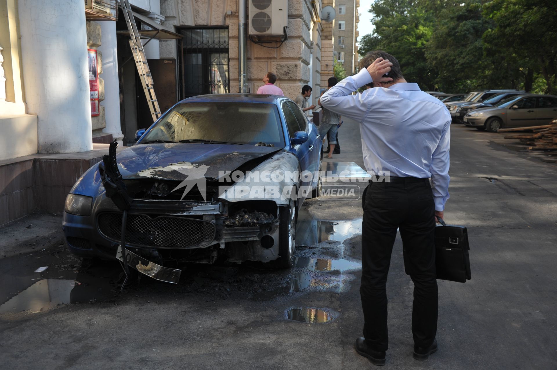 Мужчина стоит у сгоревшего автомобиля. 15 августа 2011 года.