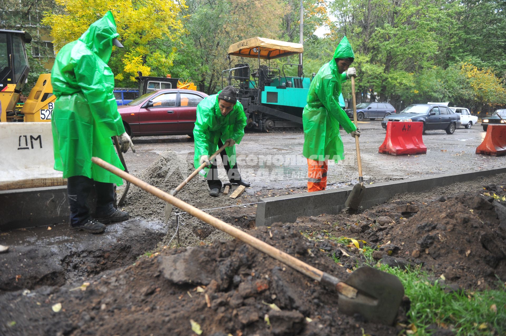 Гастарбайтеры в дождевиках в дождь занимаются установкой бордюрных плит, 23 сентября 2011 года, Москва