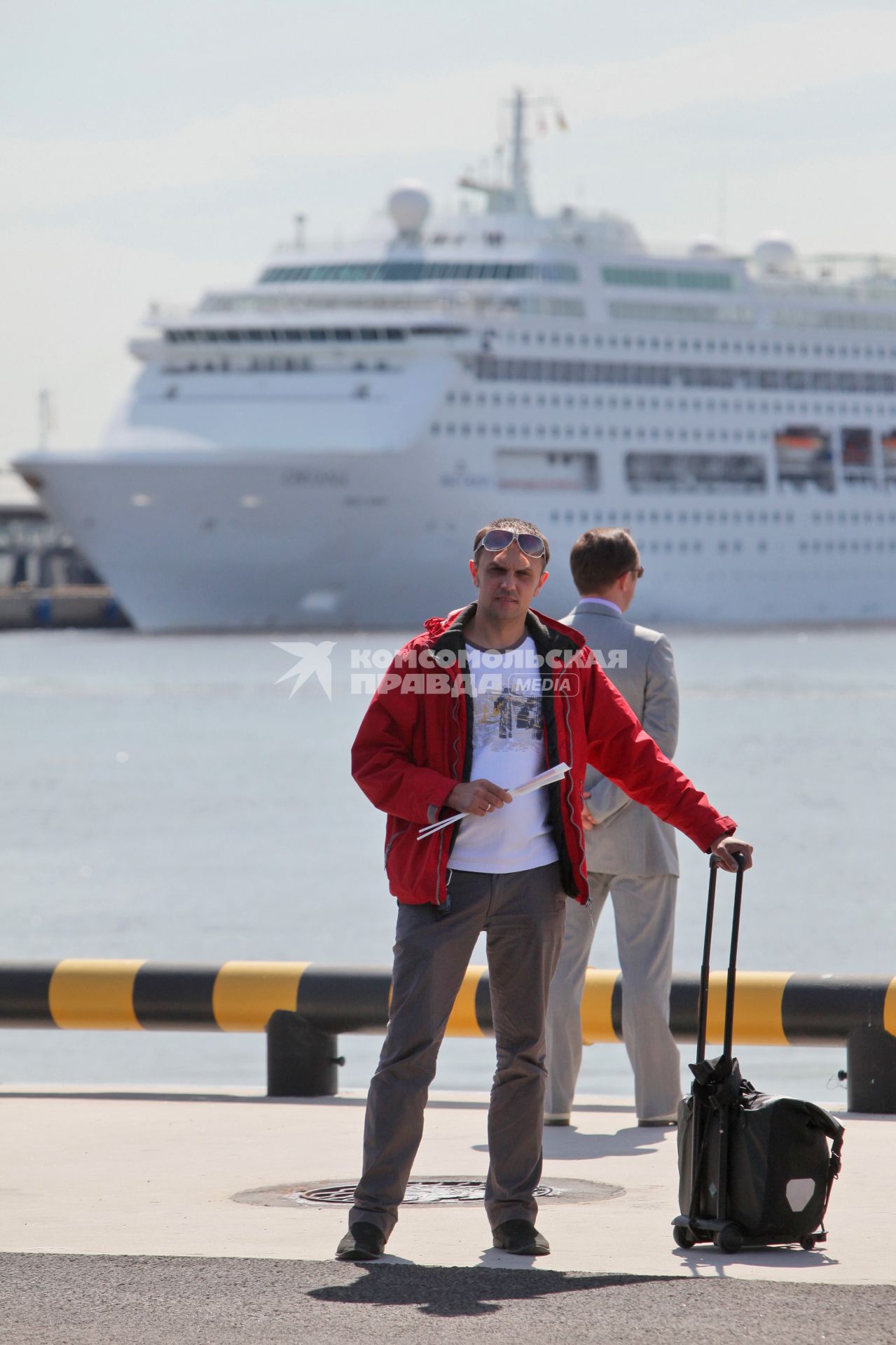 Открытие порта МОРСКОЙ ФАСАД Спб. Мужчина с багажом стоит в порту в ожидании на фоне морского круизного корабля ORIANA. 27 мая 2011 года.