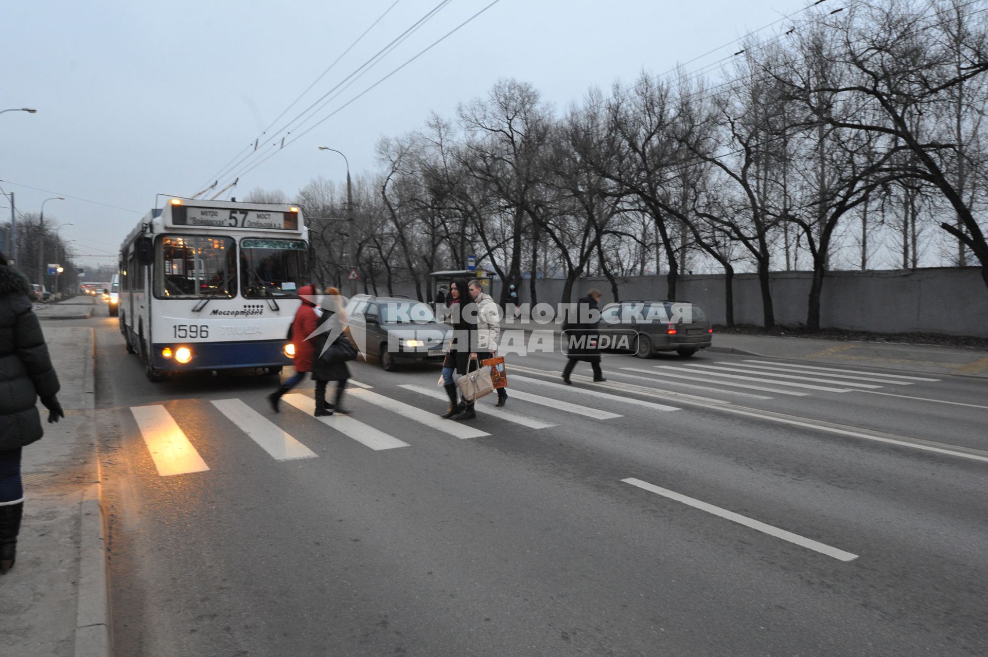 Люди переходят дорогу по пешеходному переходу.  Троллейбус уступает дорогу пешеходам. 01 декабря 2011 года.