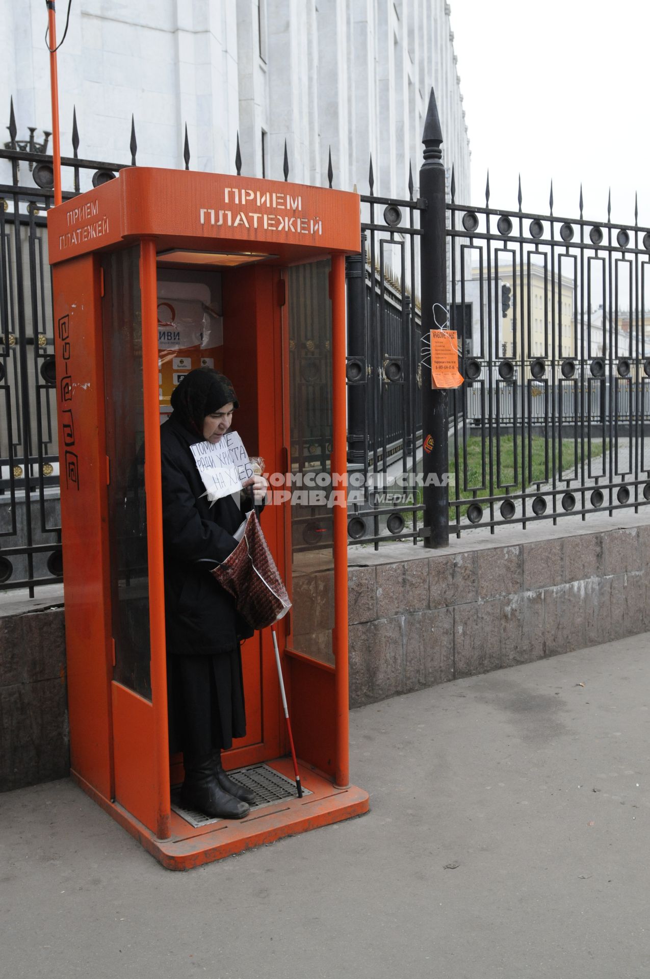 Жанровая фотография. Женщина просит милостыню в кабинке приема платежей на улице. 04 декабря  2009 года.