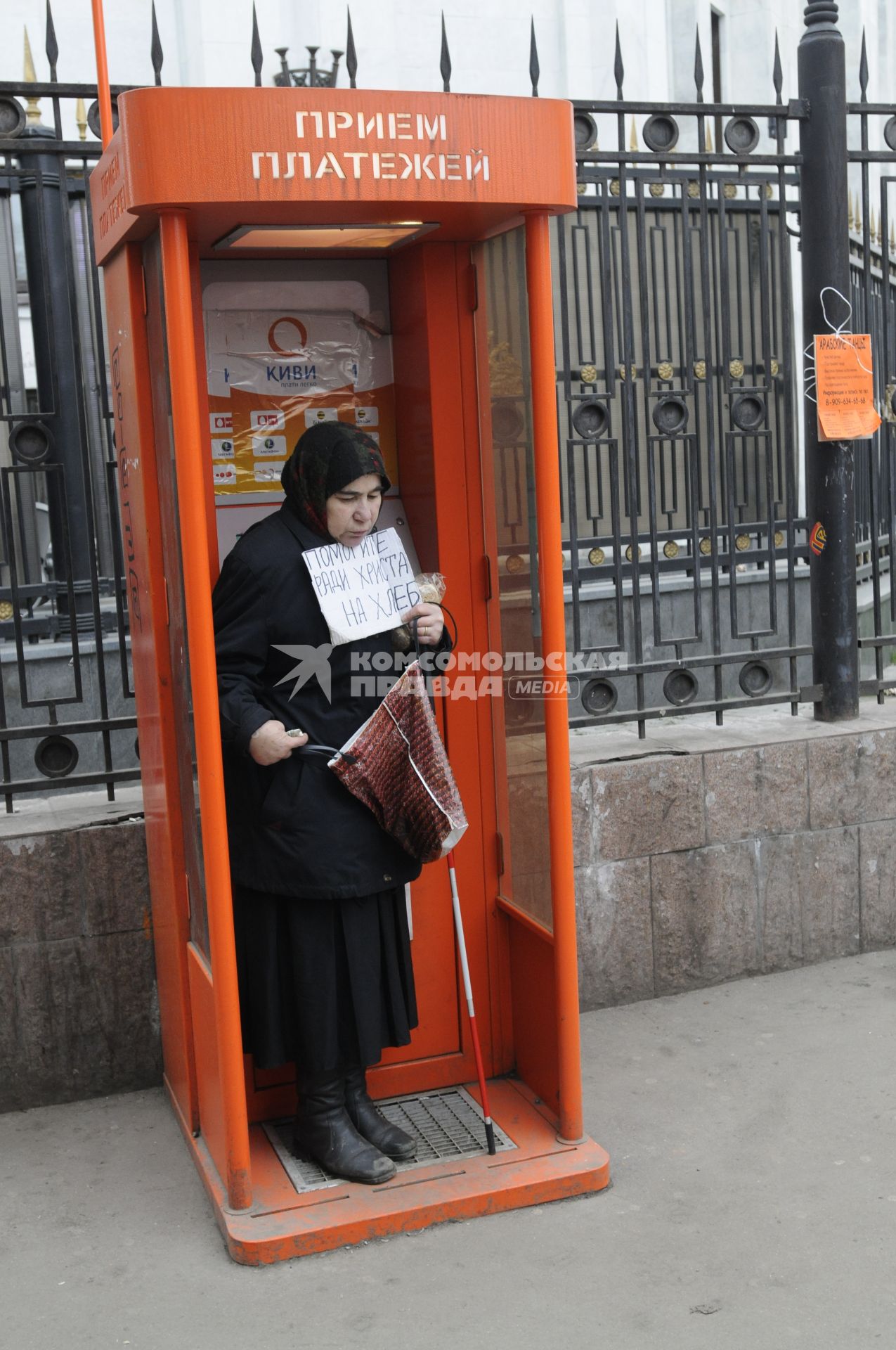 Жанровая фотография. Женщина просит милостыню в кабинке приема платежей на улице. 04 декабря  2009 года.