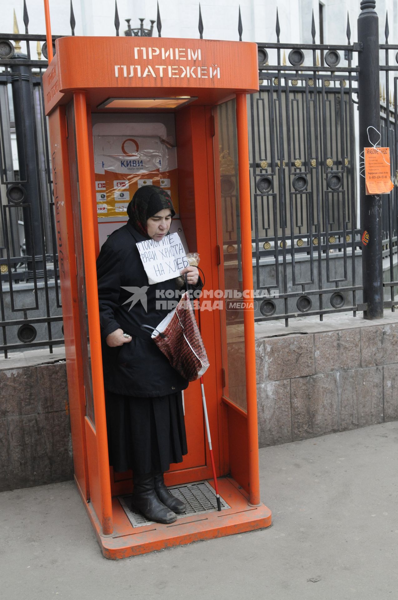 Жанровая фотография. Женщина просит милостыню в кабинке приема платежей на улице. 04 декабря  2009 года.