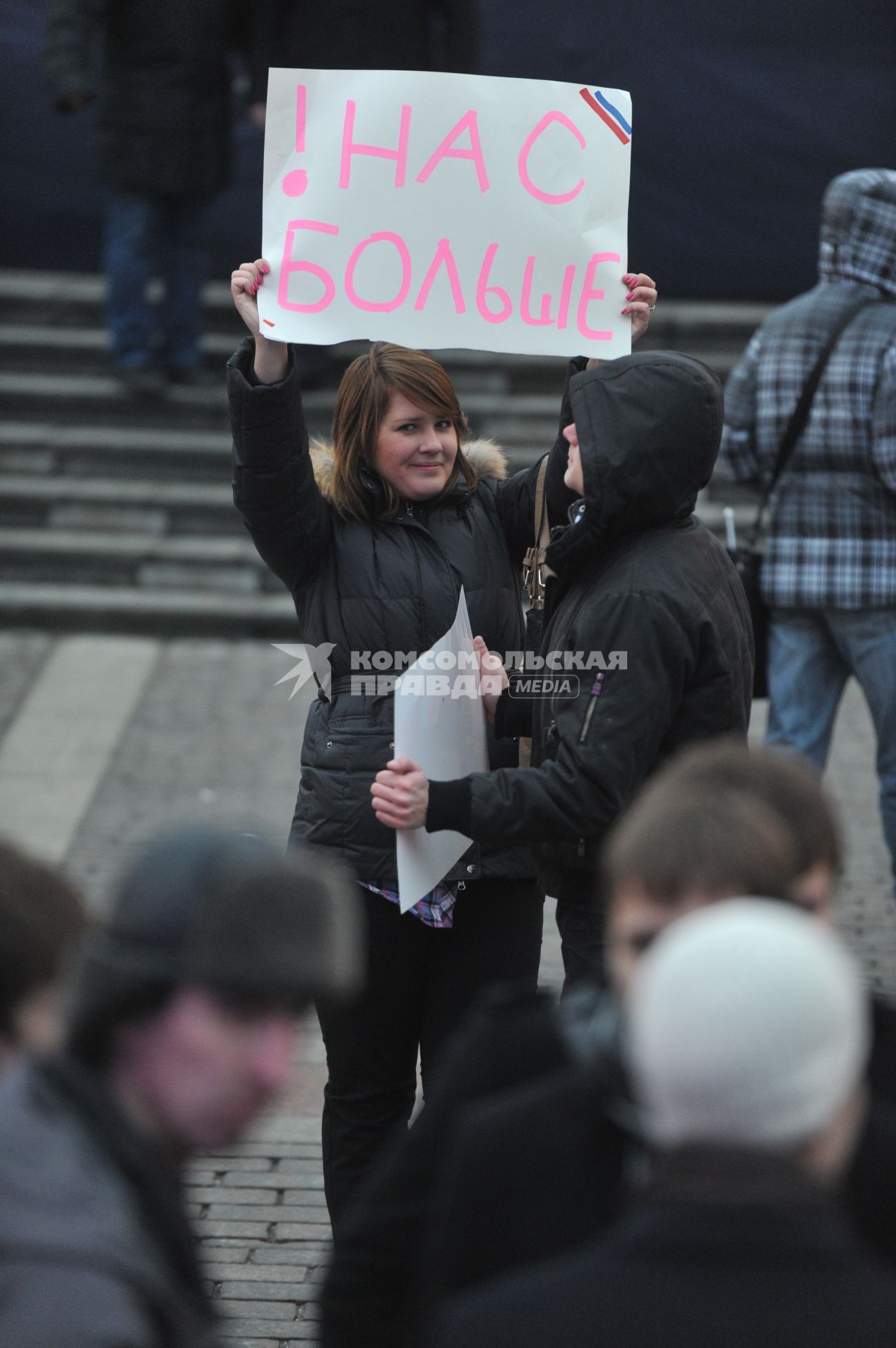 Участники митинга сторонников президента РФ Дмитрия Медведева и премьер-министра РФ Владимира Путина СЛАВА РОССИИ! на Манежной площади. На снимке: девушка держит плакат НАС БОЛЬШЕ. 12 декабря  2011 года.