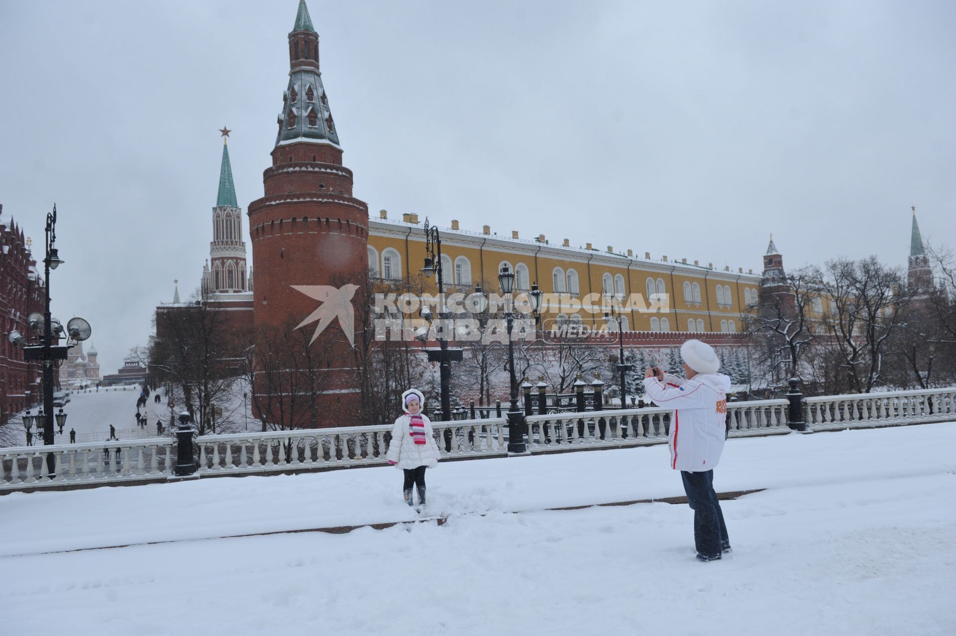 Жанровая фотография. Зимняя прогулка с мамой. На снимке: женщина фотографирует девочку на фоне Кремлевской башни.  Москва. 21 декабря  2011 года.