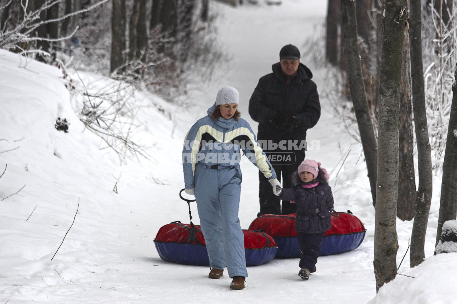 Семья (мама папа ребенок) собираются кататься со снежной горки на тюбингах. 5 января 2012 года.