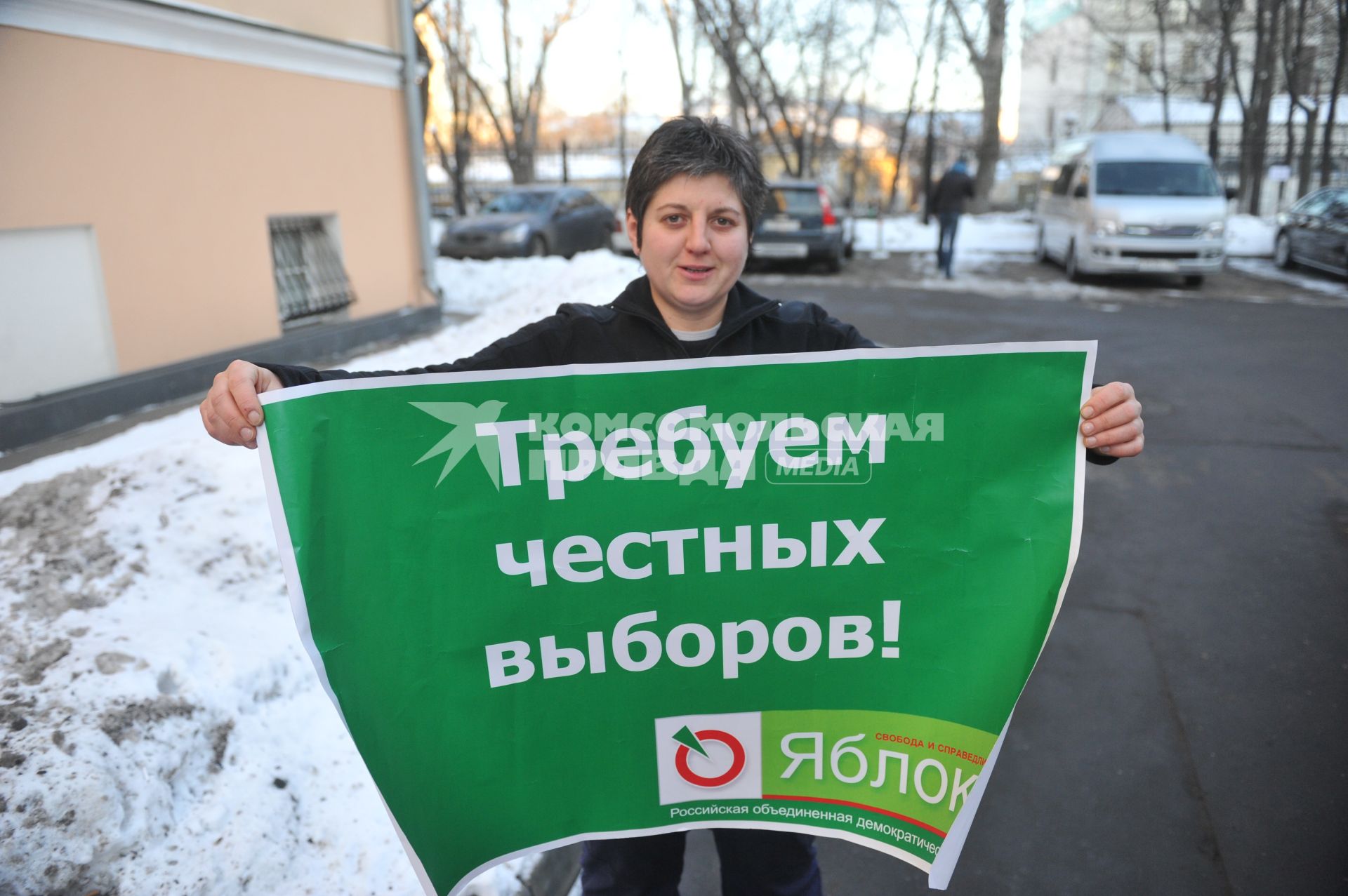 Женщина держит плакат пратии ЯБЛОКО с надписью ТРЕБУЕМ ЧЕСТНЫХ ВЫБОРОВ!. 27 января 2012 года.