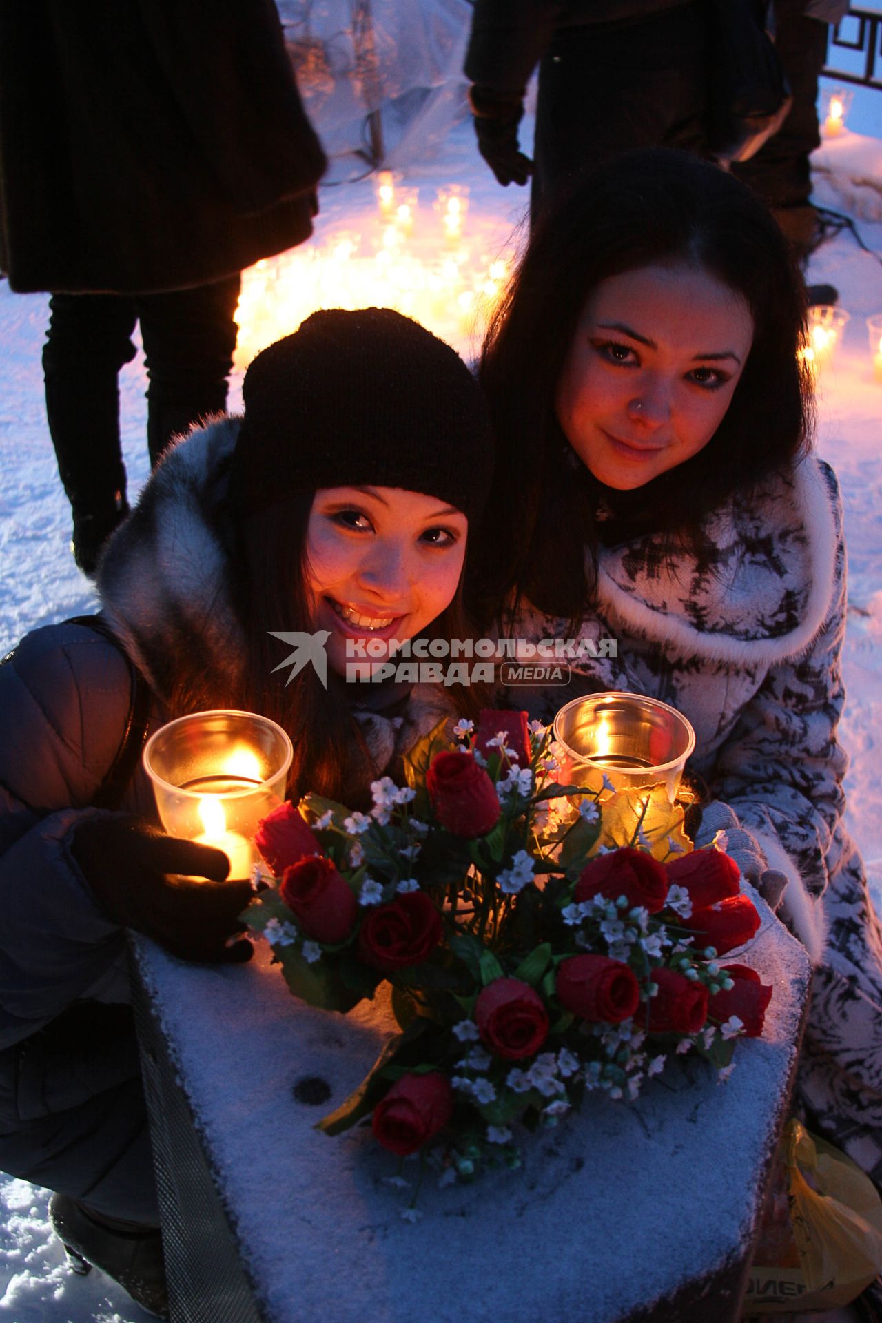 Девушки сидят около композиции со свечами и букетом цветов.