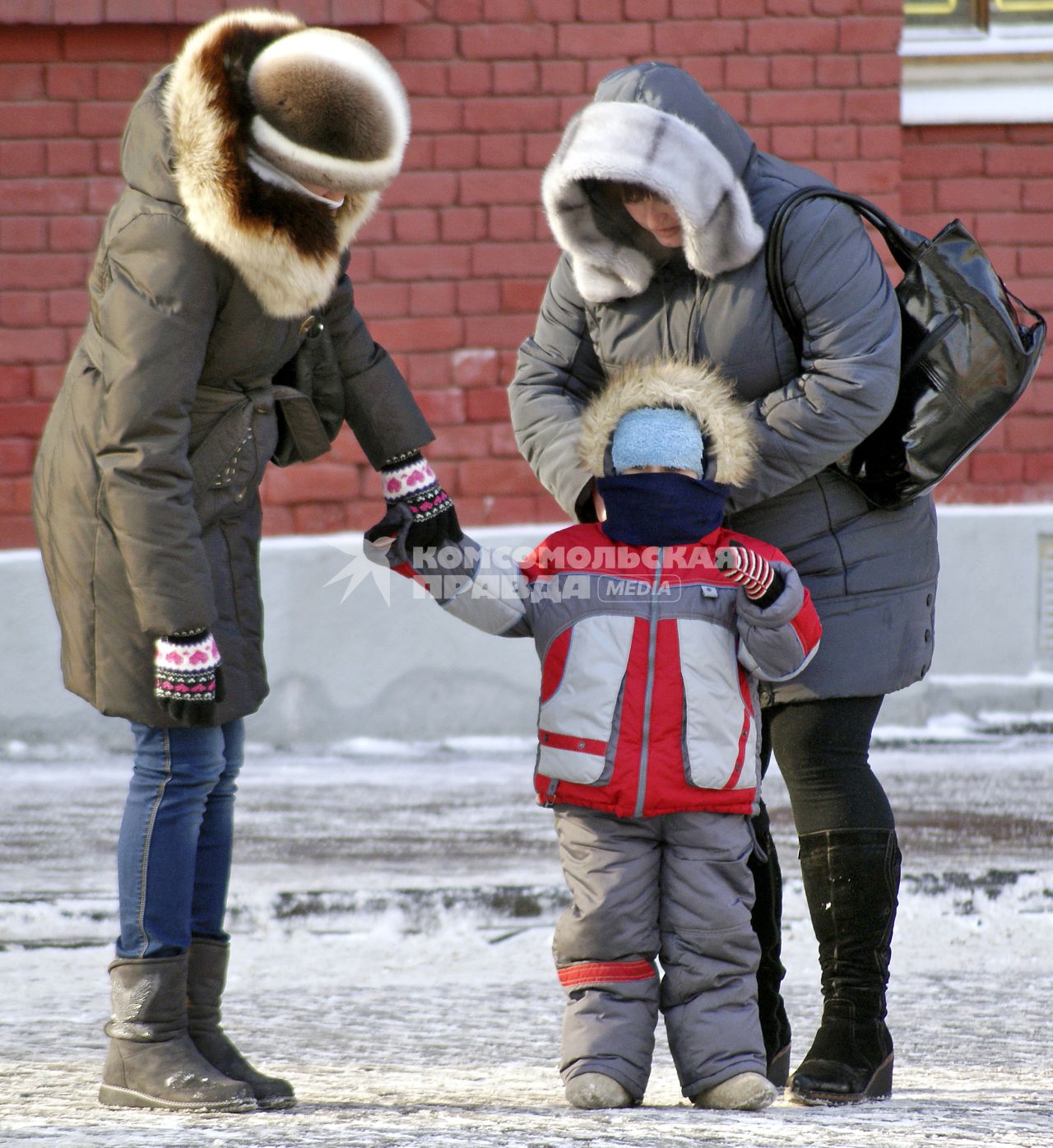 Родители укутывают ребенка. Мама повязывает шарф.