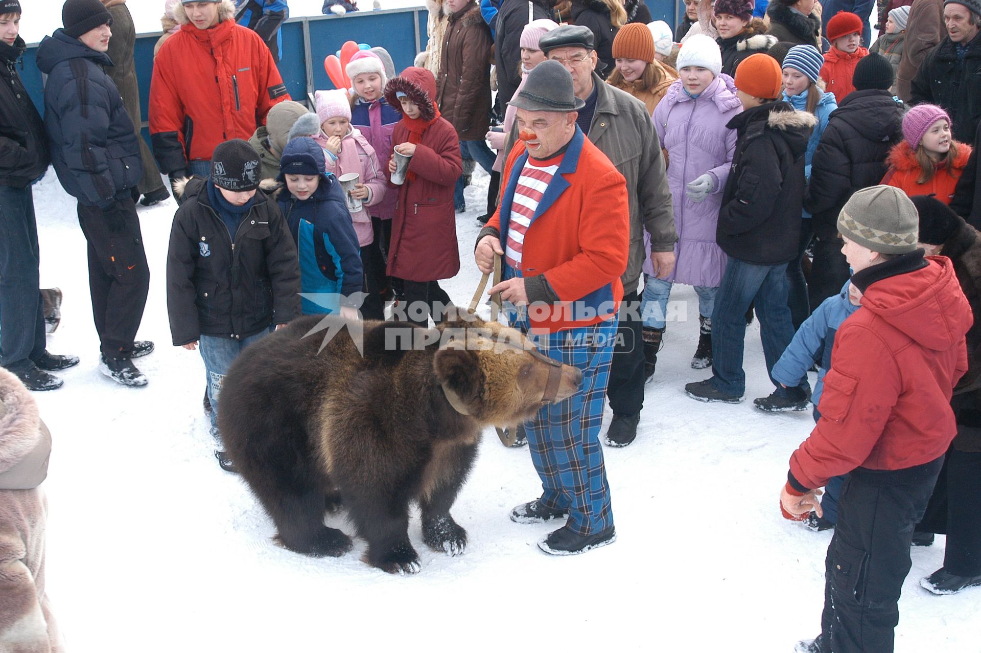 Мужчина стоит посреди зевак с дрессированным медведем.