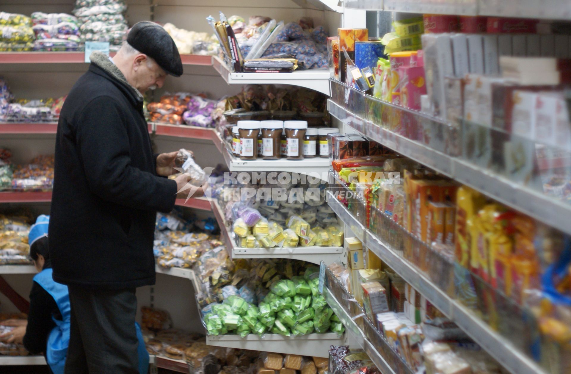 Мужчина у прилавка магазина осматривает продукты.